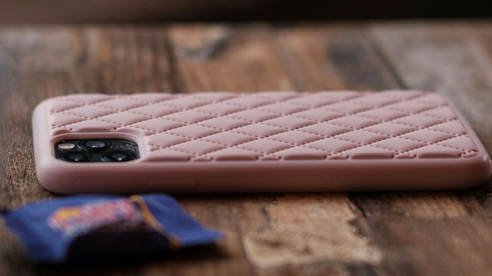 A pink cell phone sitting on top of a wooden table