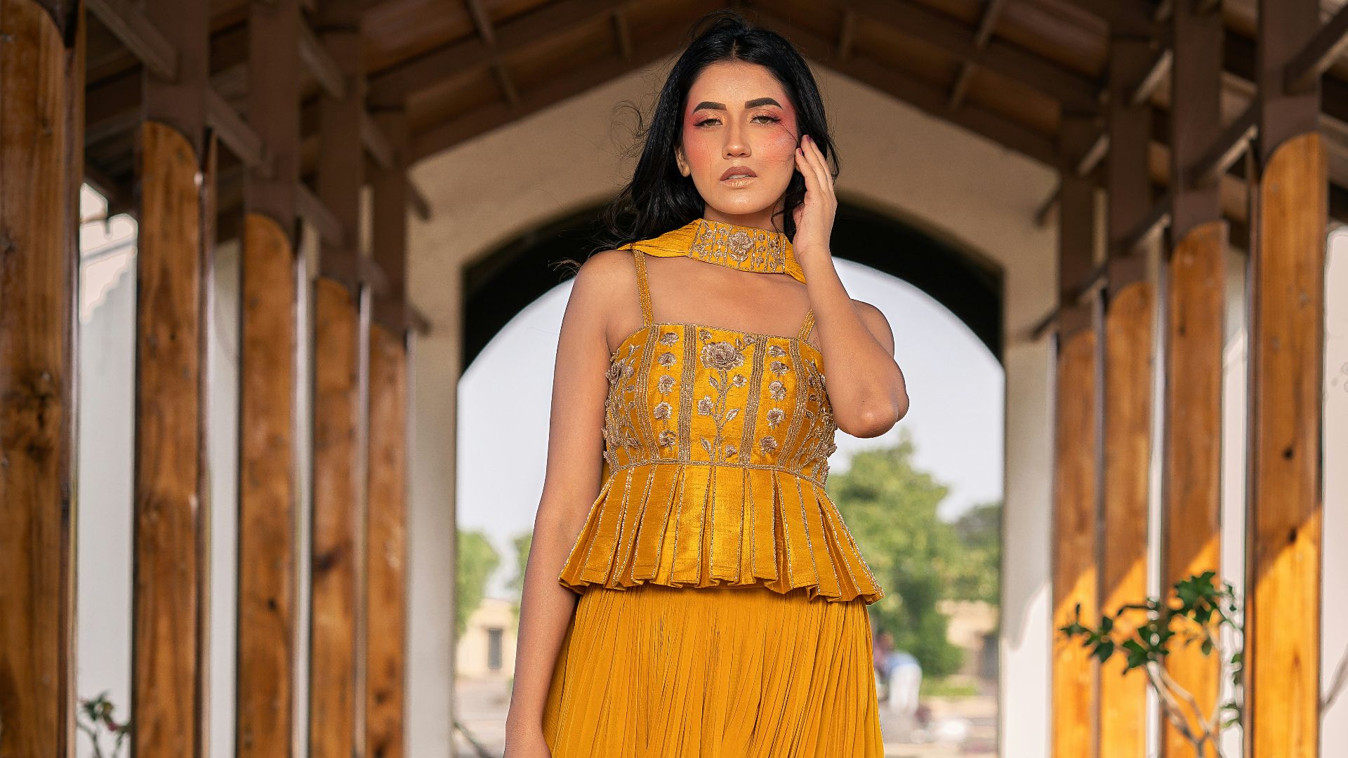 Woman in yellow dress walks through wooden archway
