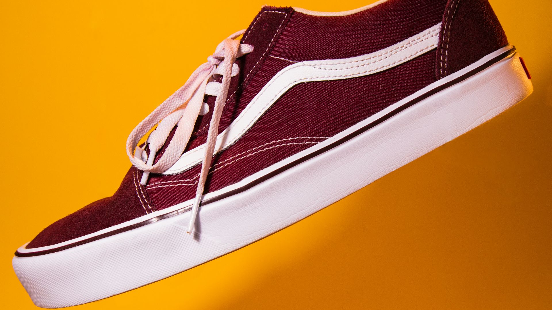 unpaired maroon plimsoll on top of yellow textile