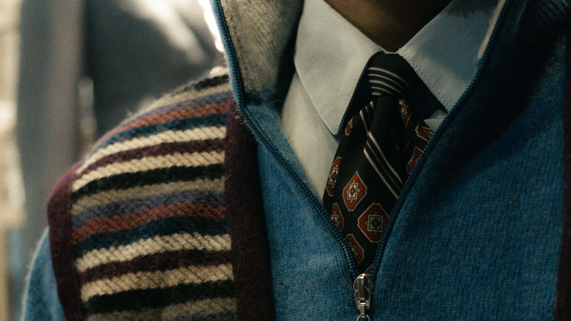 Man wearing a blue quarter-zip sweater over a collared shirt.