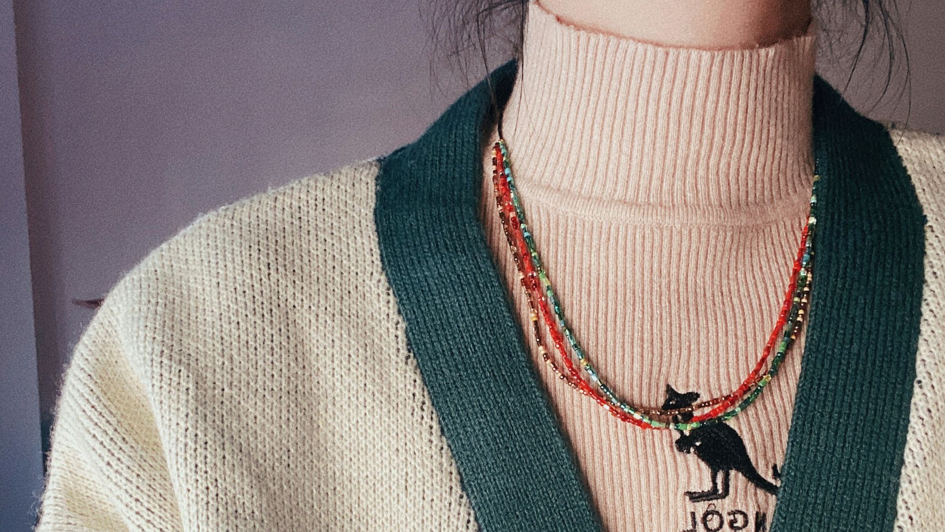 a person wearing a sweater and a necklace