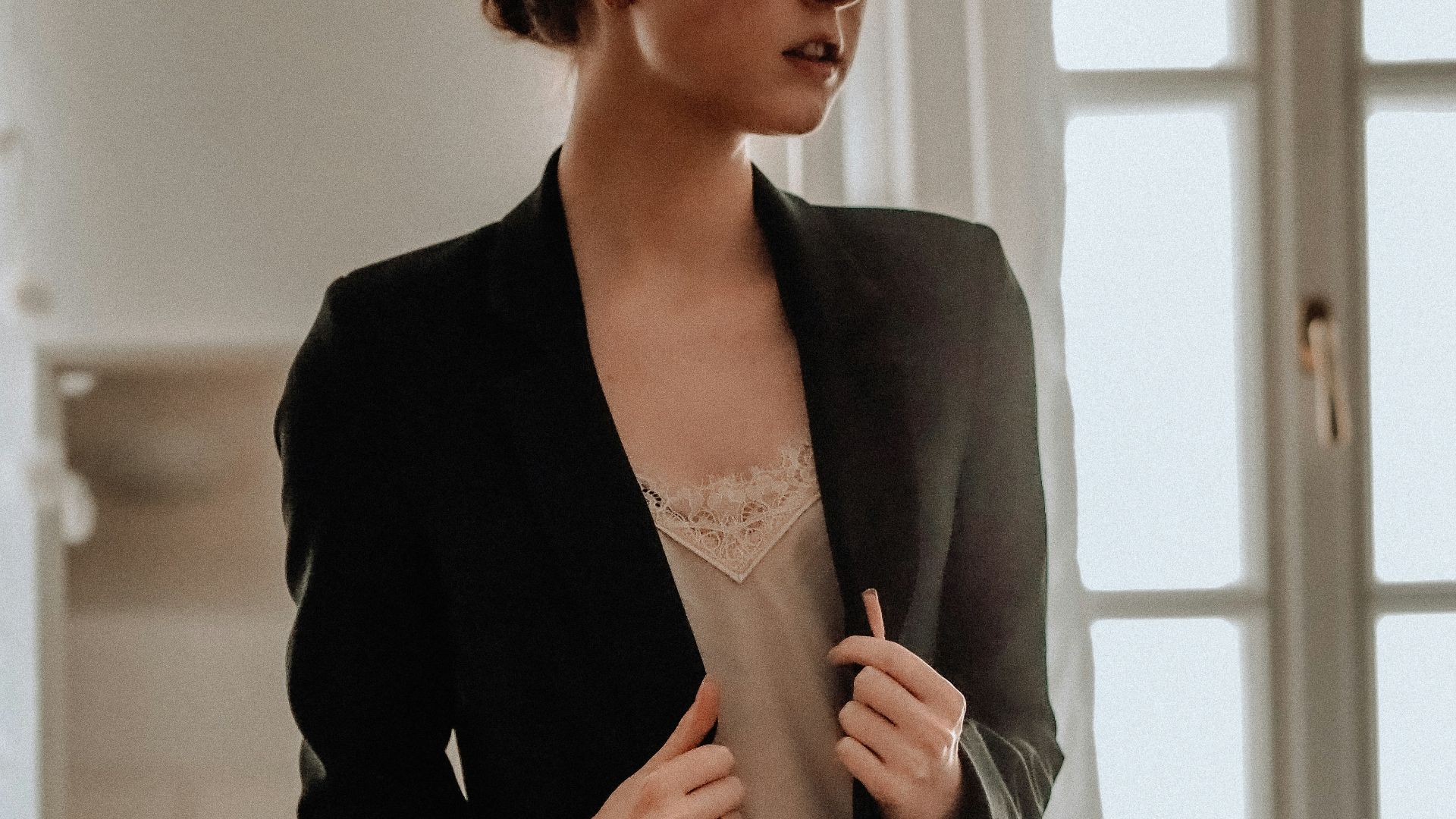 woman in black blazer standing near white wall