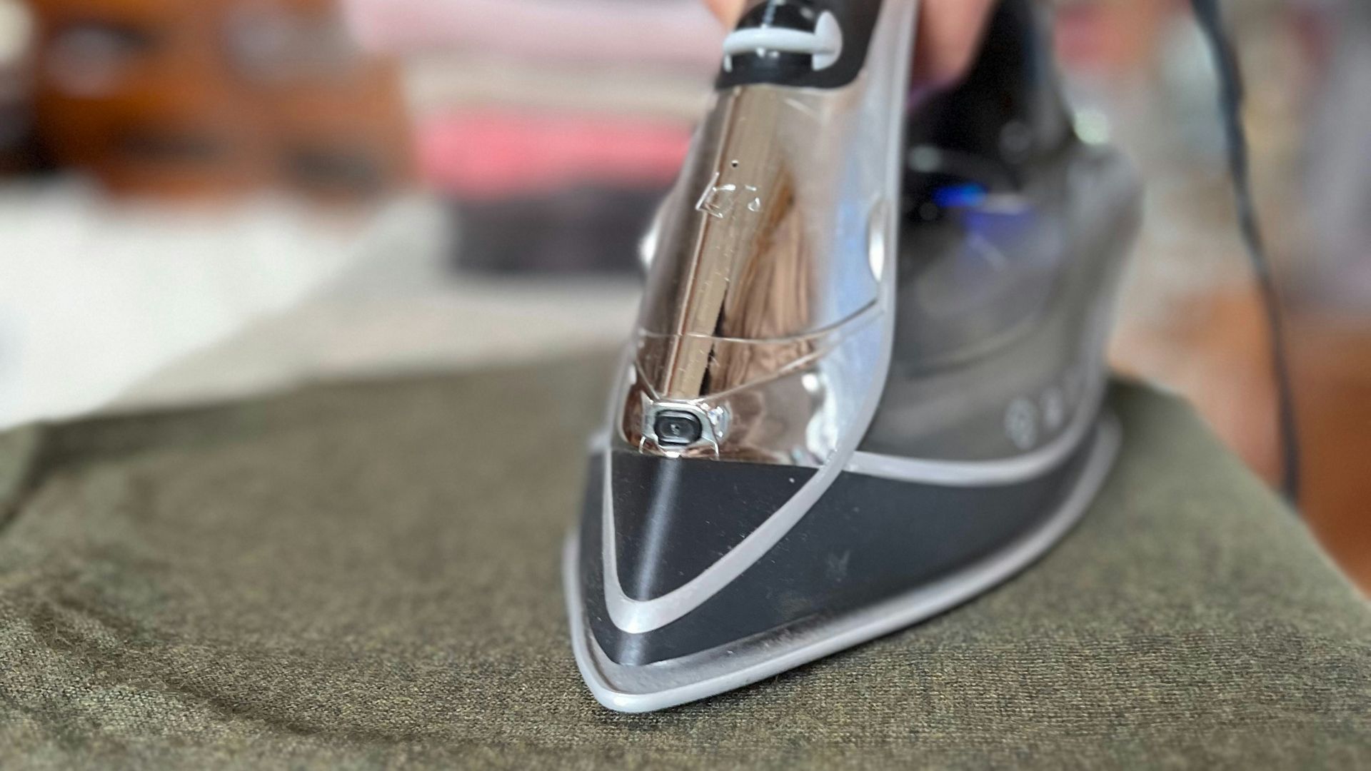 A person ironing a green shirt with a black iron