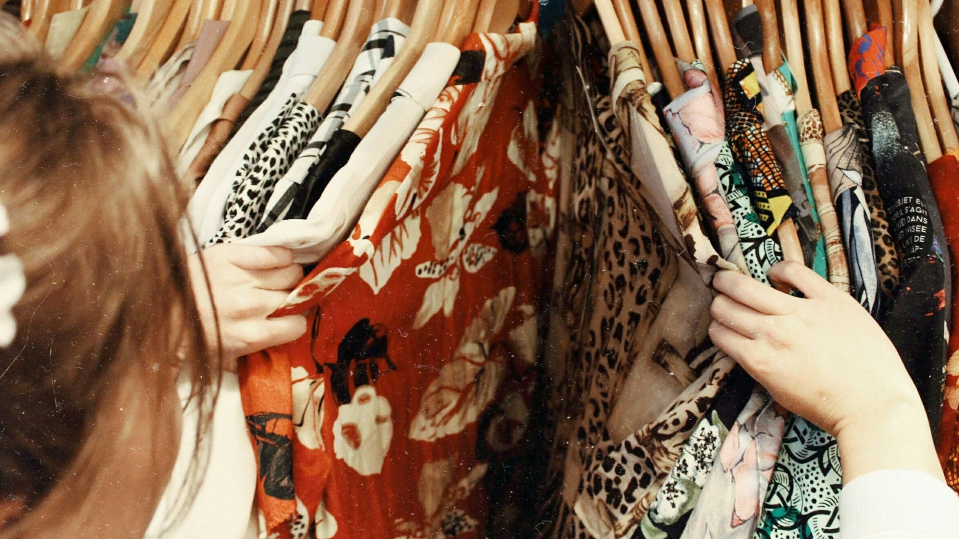 person holding assorted clothes in wooden hanger