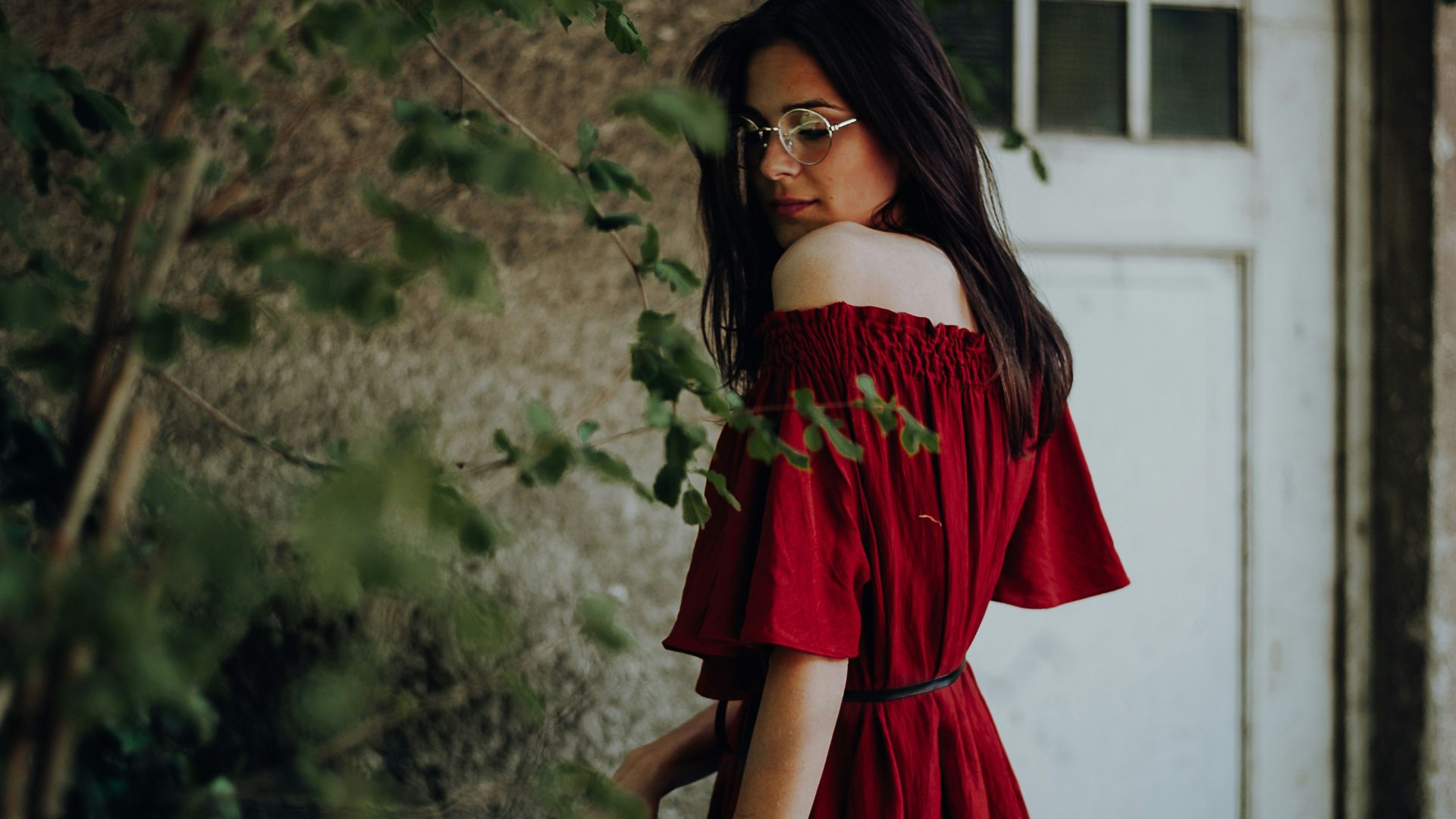 woman in red off-shoulder short-sleeved dress near brown concrete building