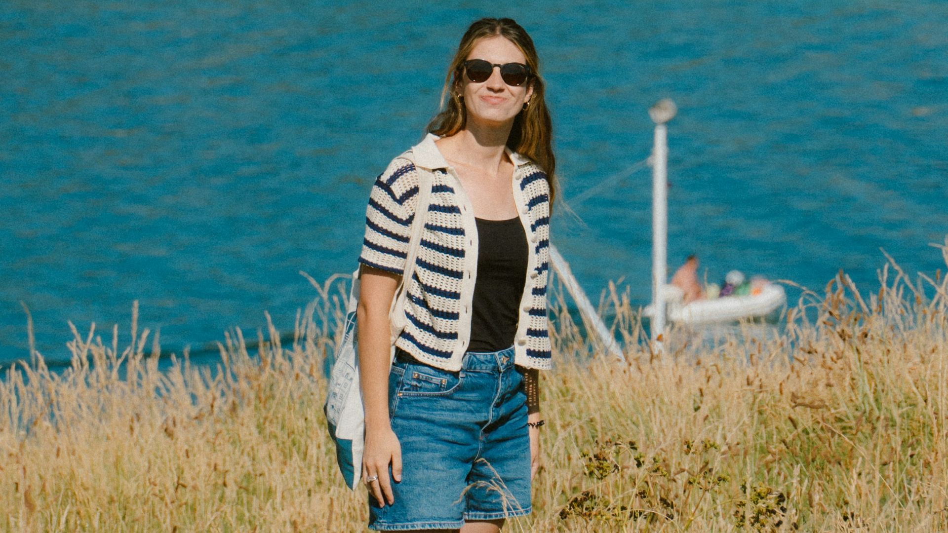 Woman standing on grassy hill overlooking bay with sailboats