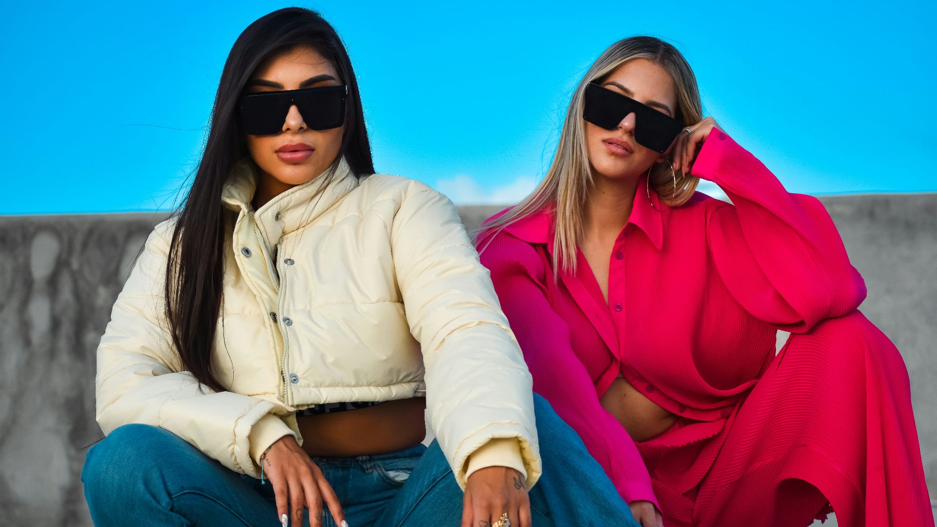 two women sitting on a wall