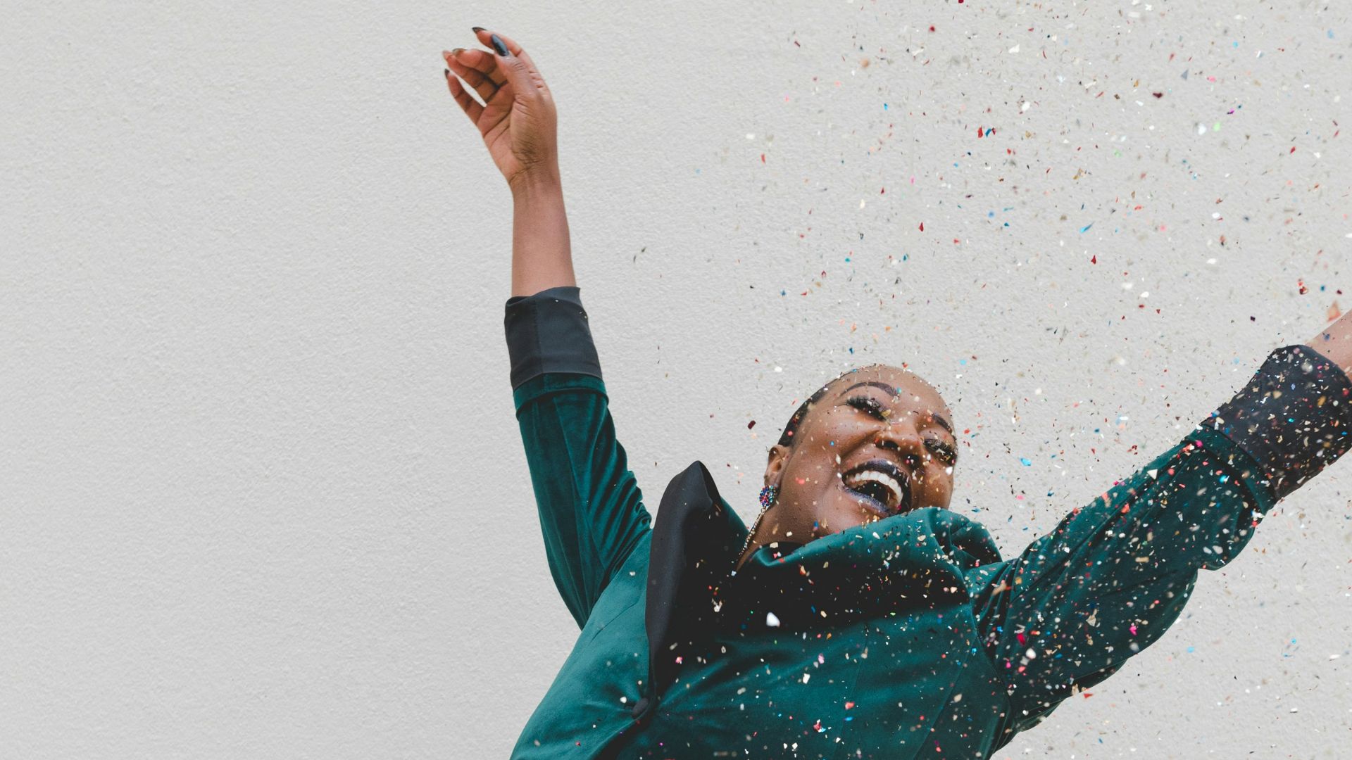 woman in green jacket raising her hands