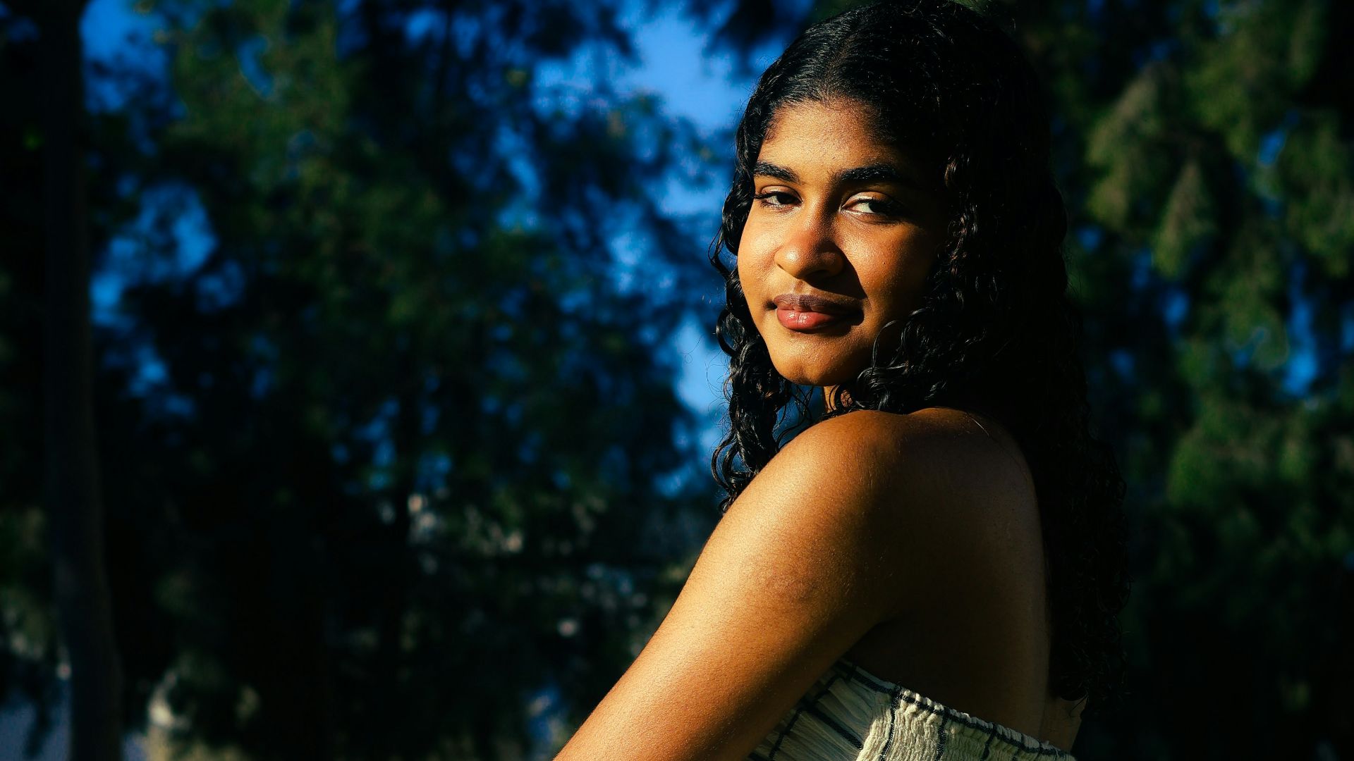 Young woman in a checkered dress kneeling outdoors