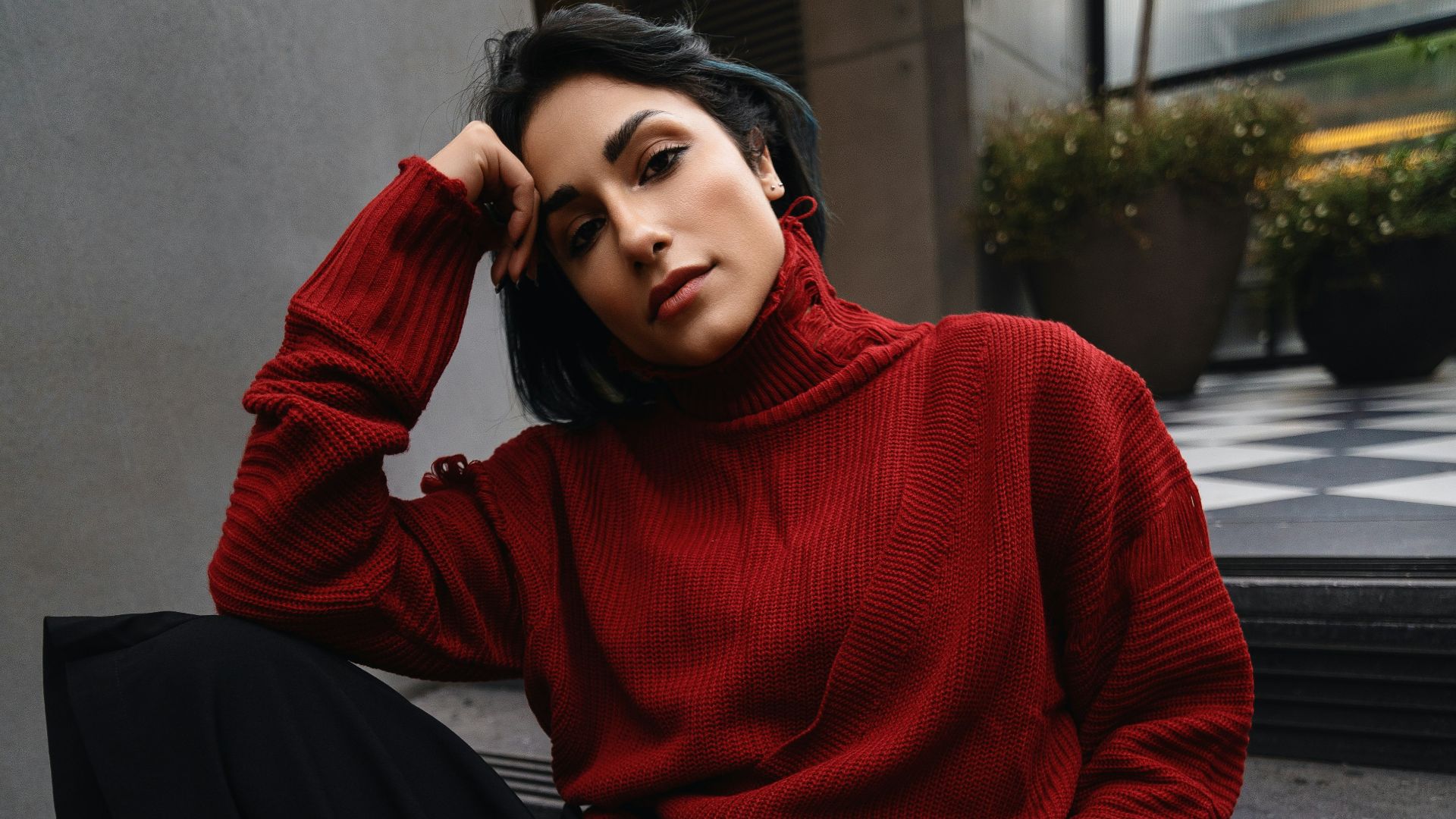 A woman in a red sweater is sitting on some stairs