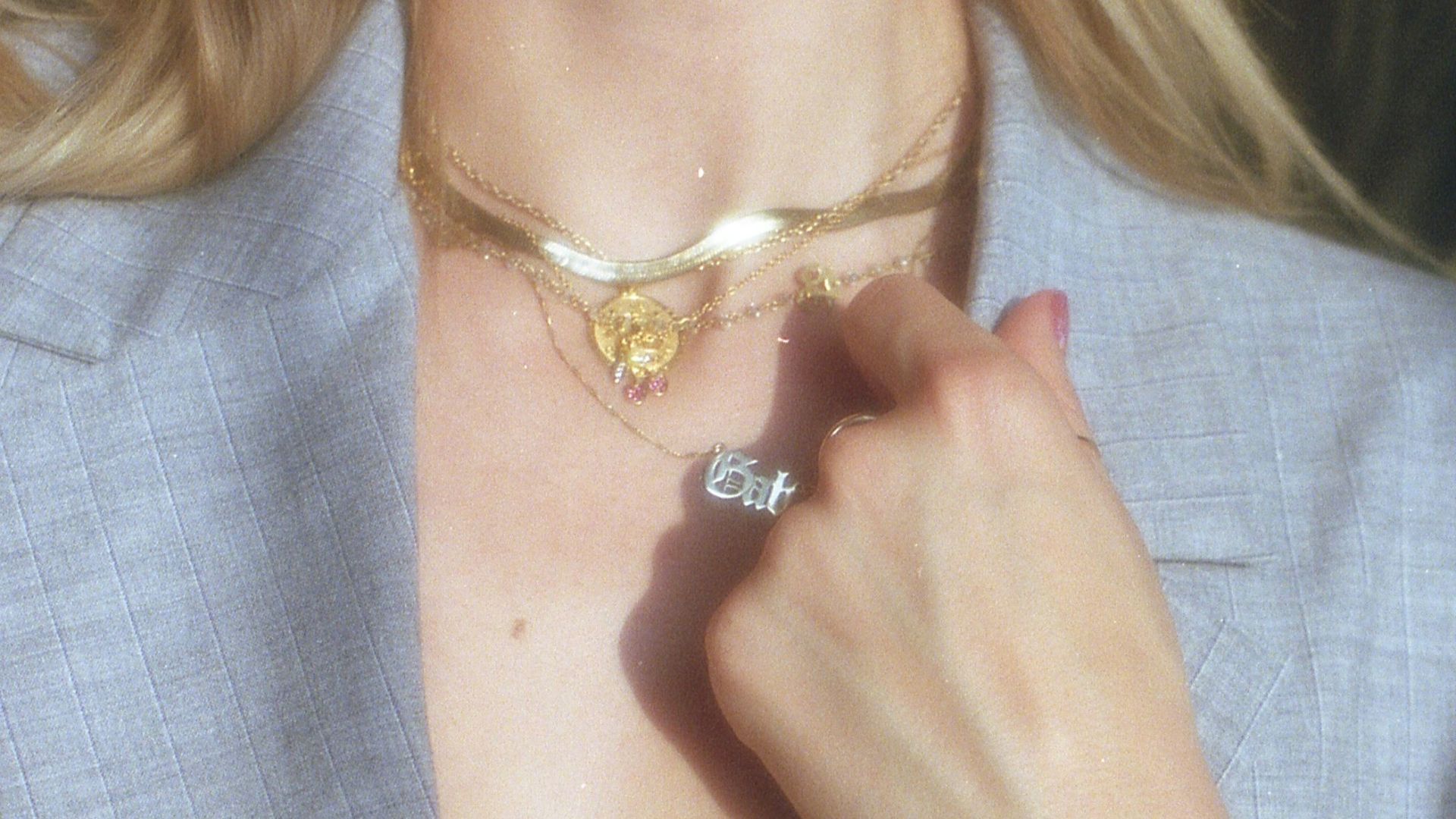 woman in gray blazer wearing gold bracelet and gold bracelet