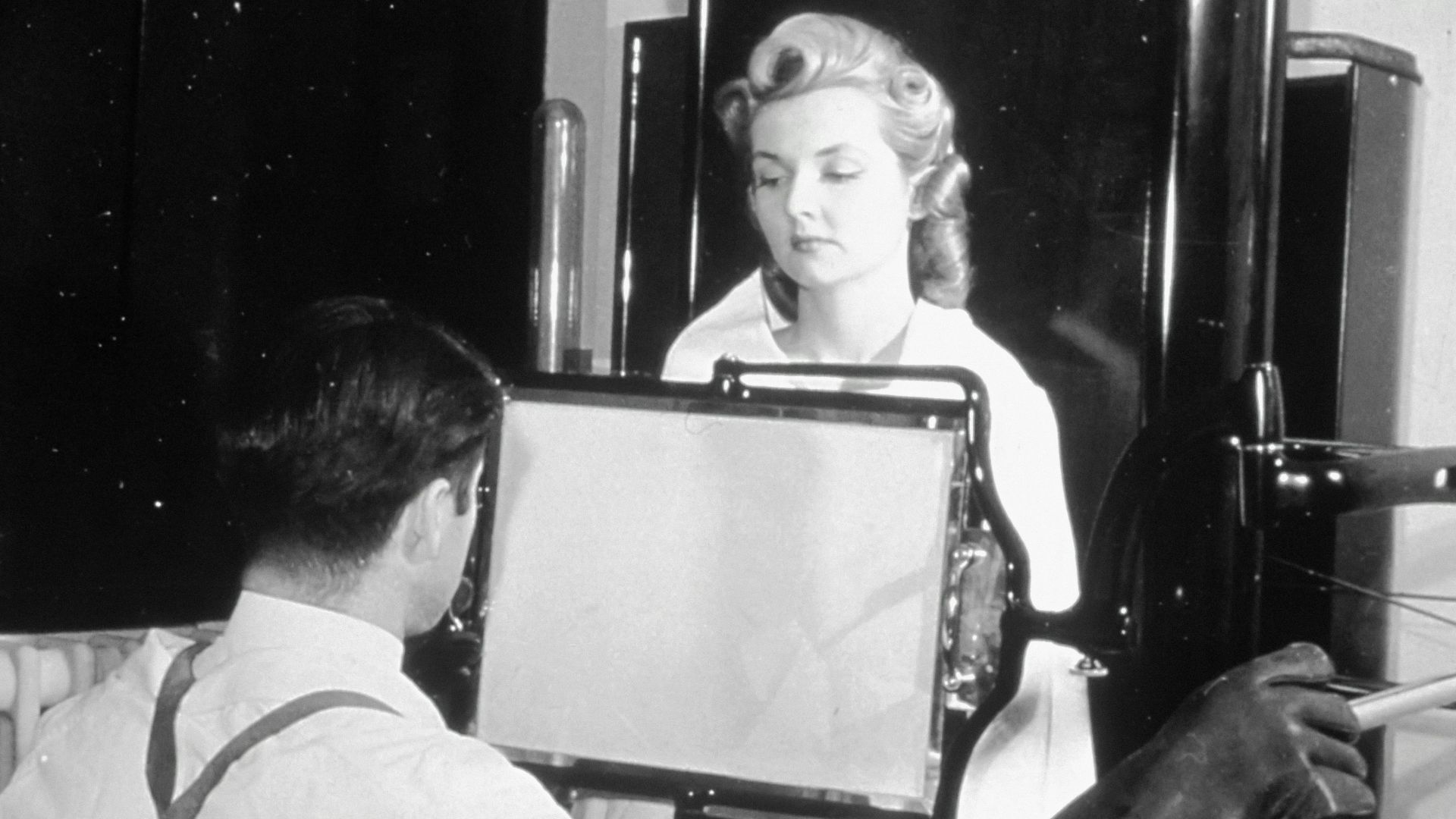 a woman sitting in a chair looking at a mirror