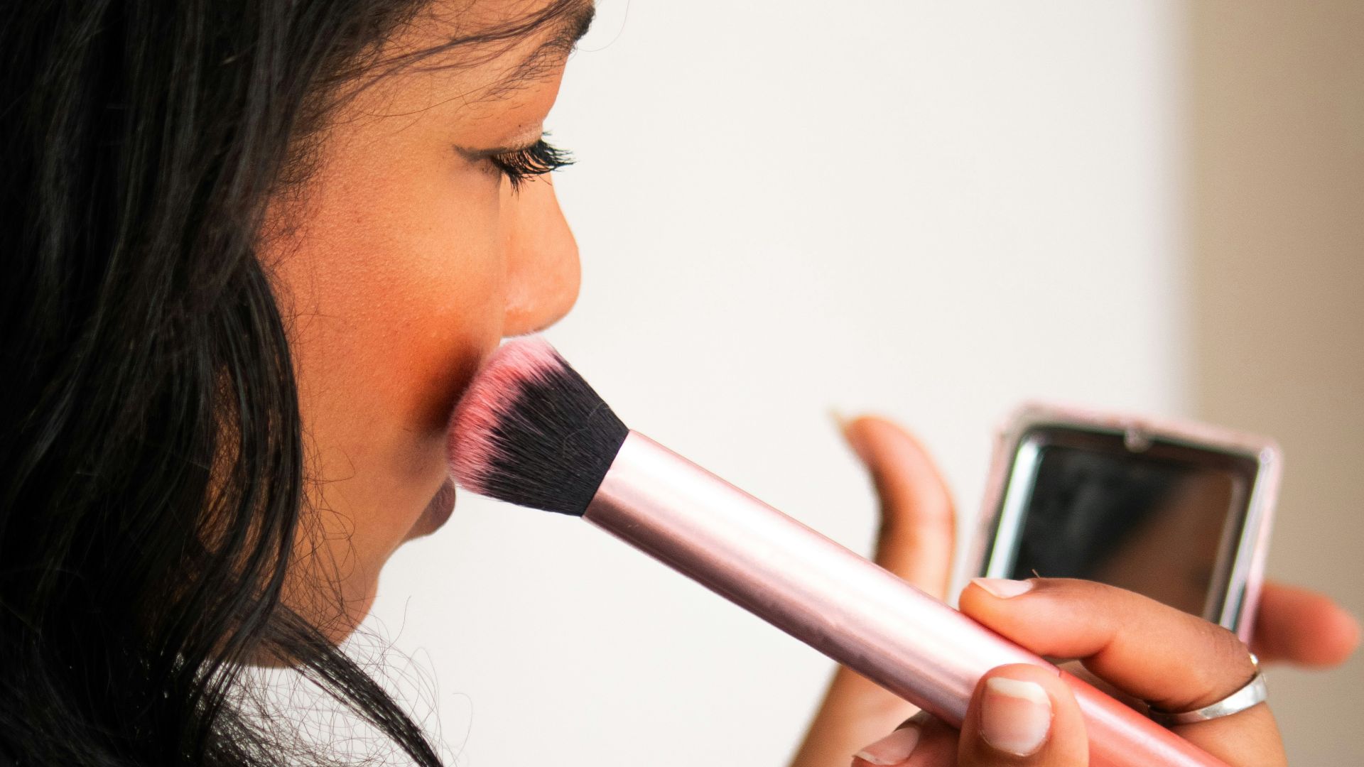 Woman applying blush with a makeup brush.