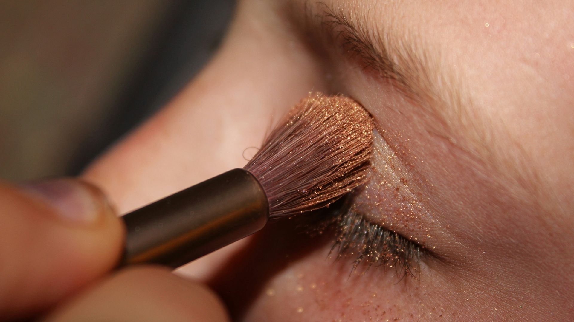 woman applying brown glittered eyeshadow