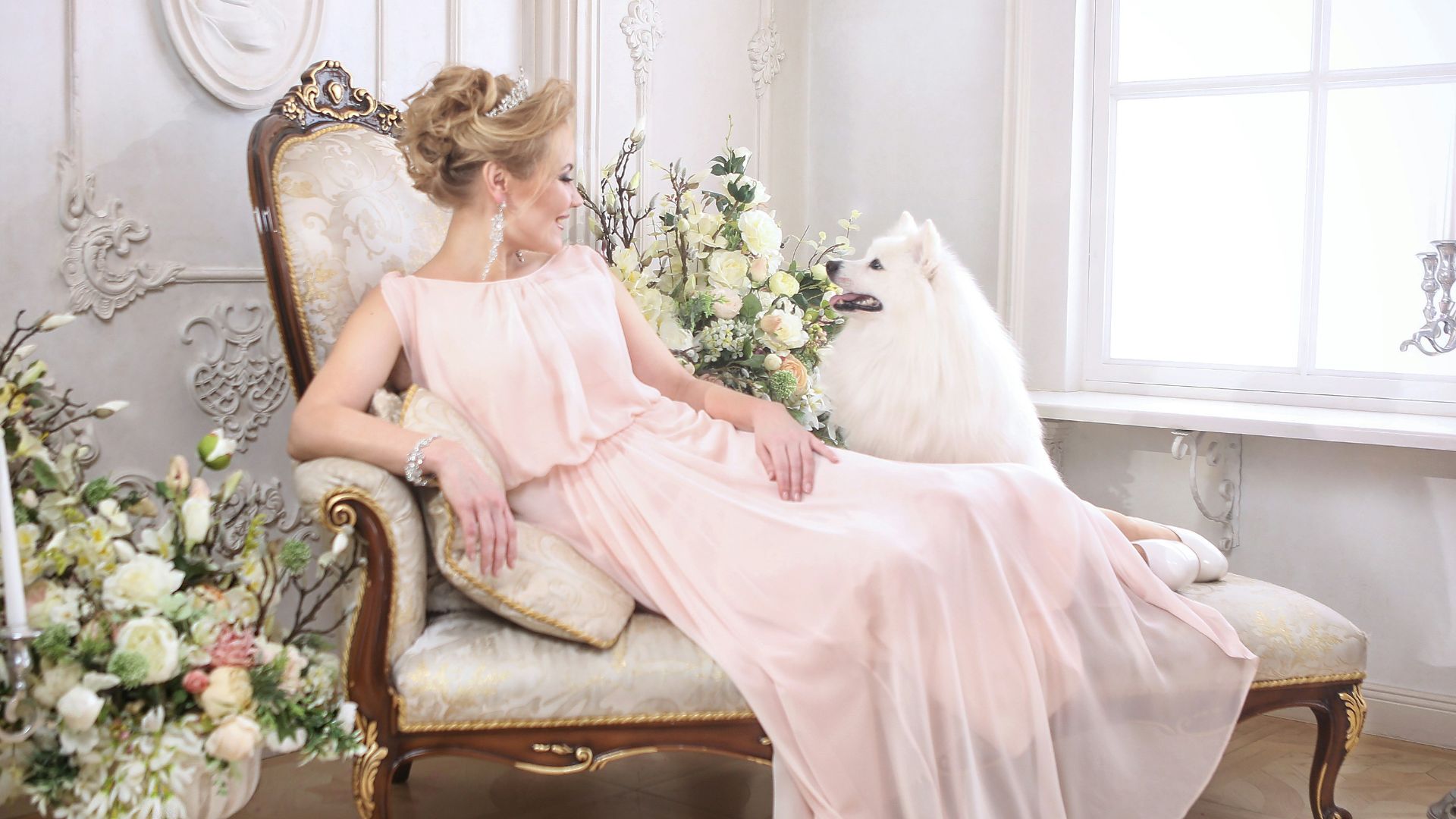 a woman in a pink dress sitting on a chair with a dog