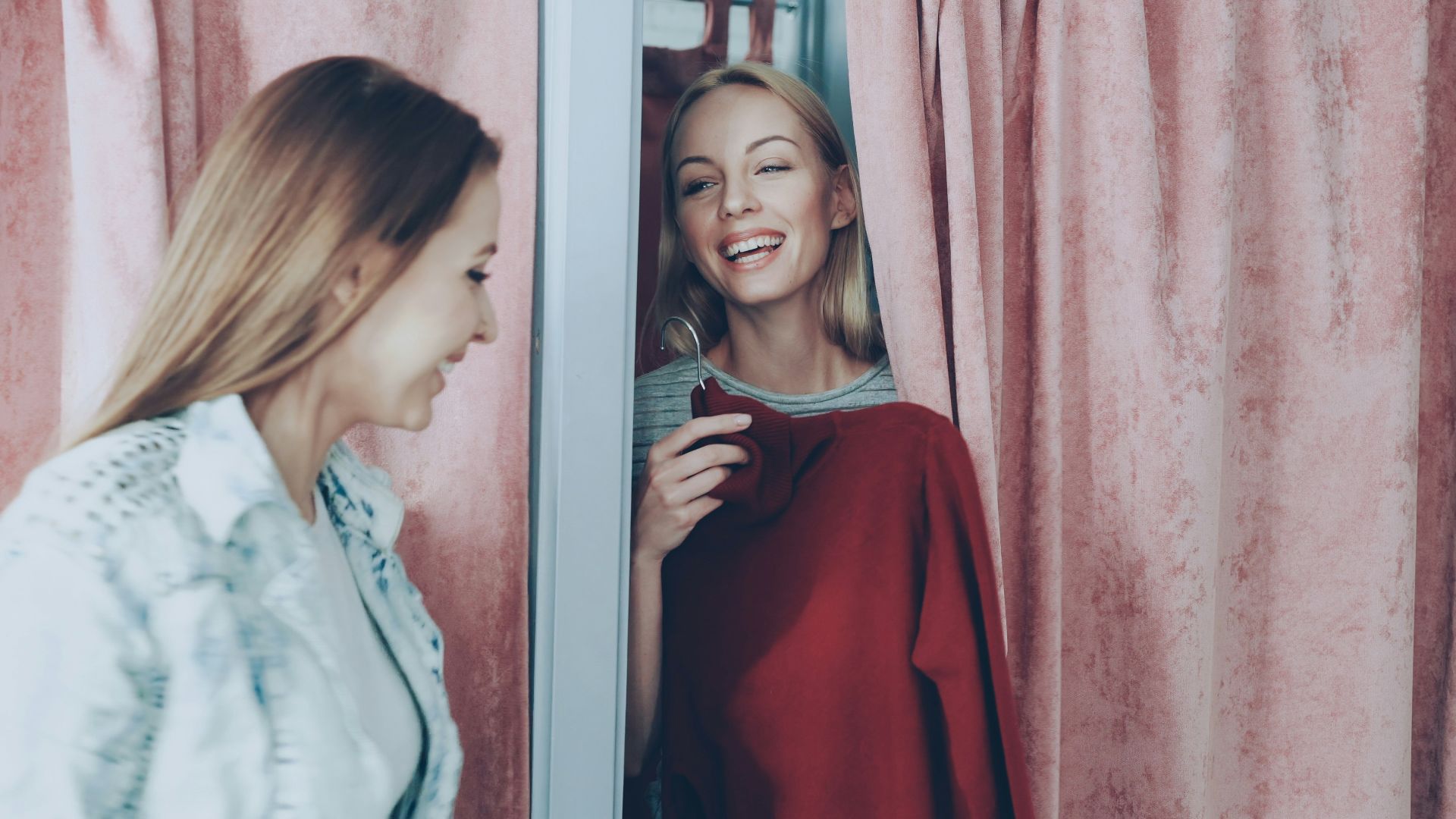 Two women are shopping and trying on clothes.