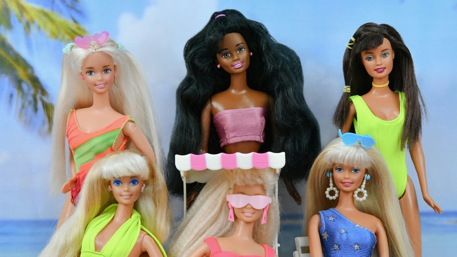 Dolls in swimsuits relaxing on a sandy beach.