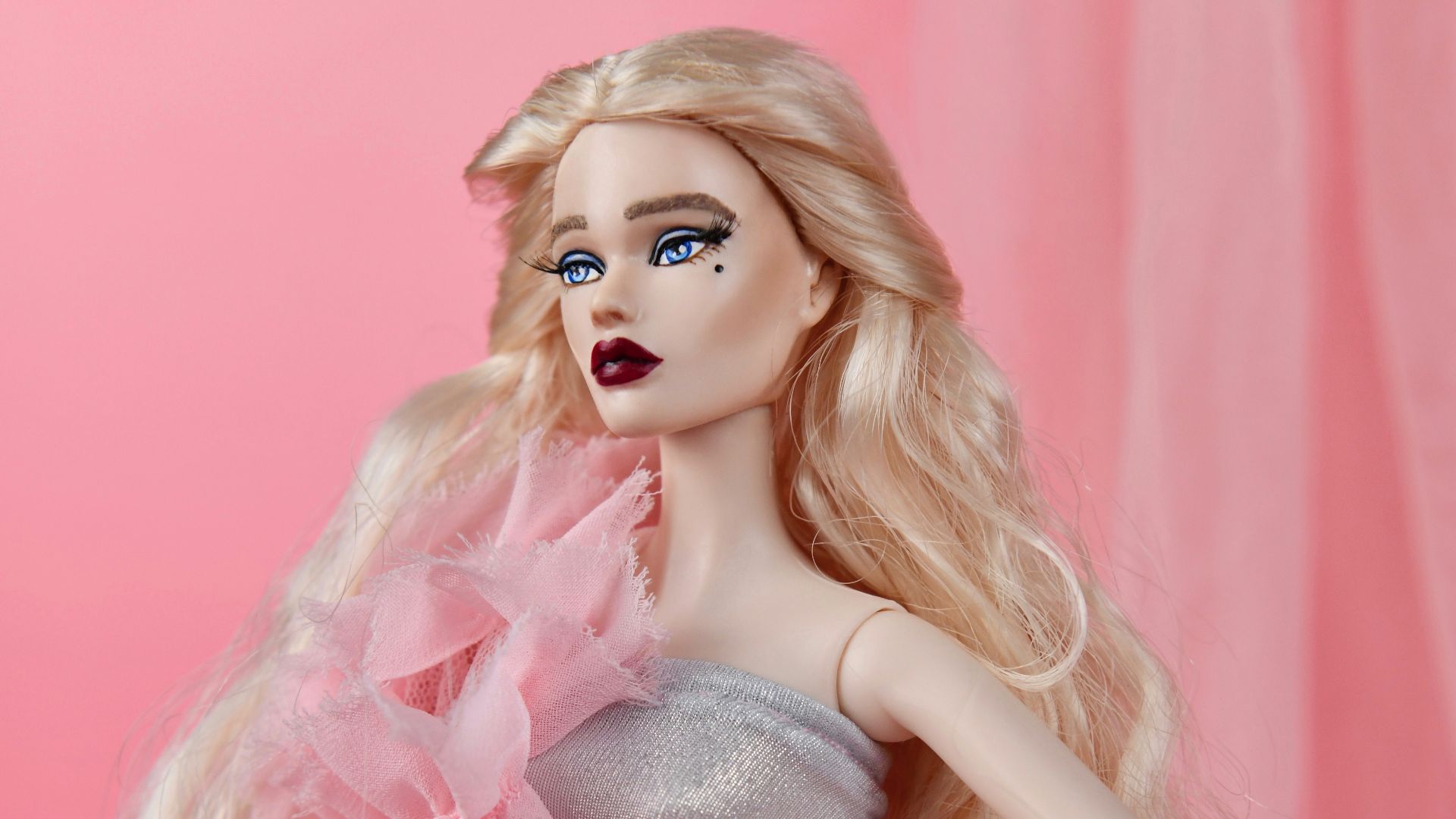 A barbie doll in a pink dress with a pink background