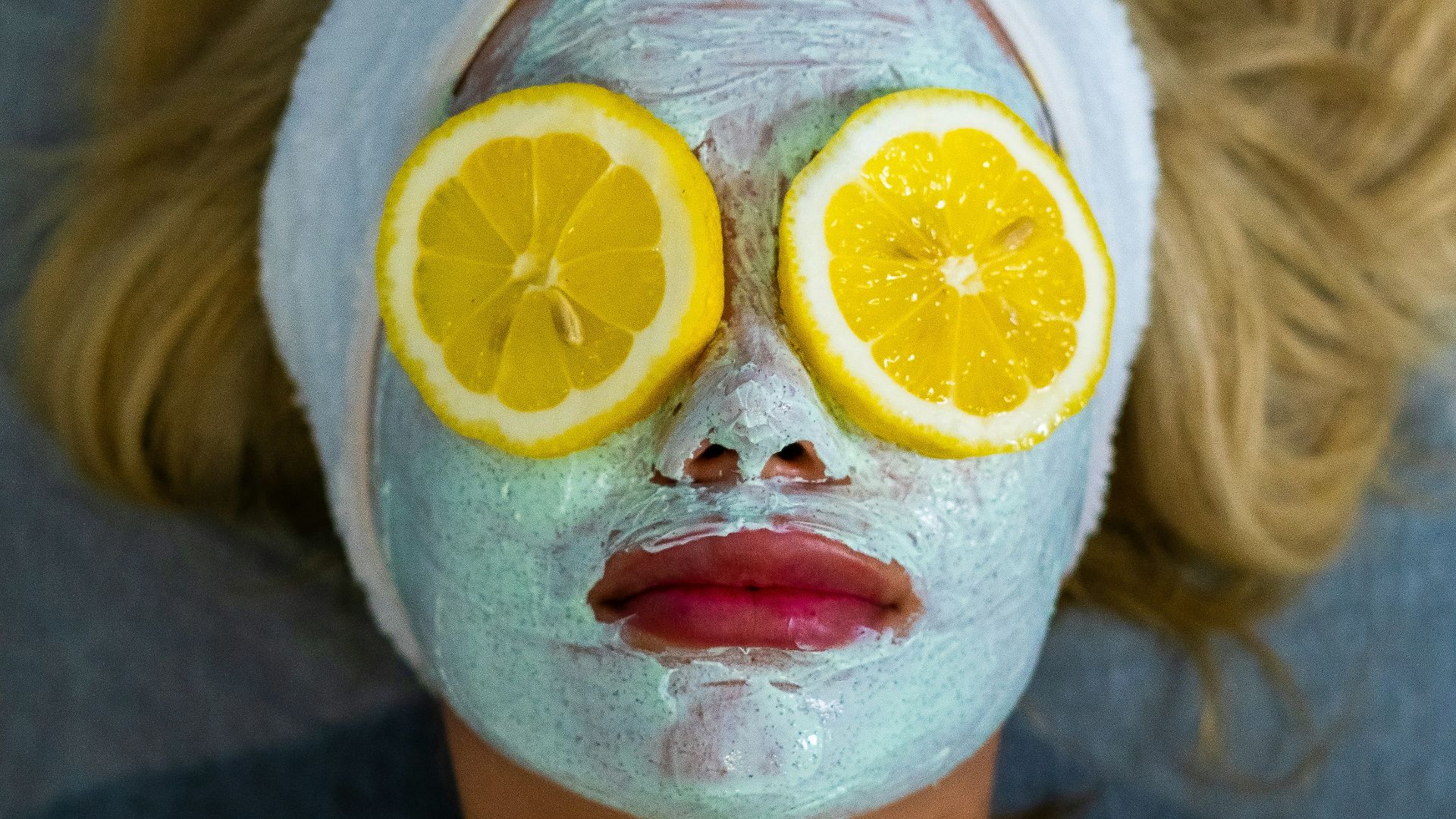 a woman with a towel on her head and two slices of lemon on her face