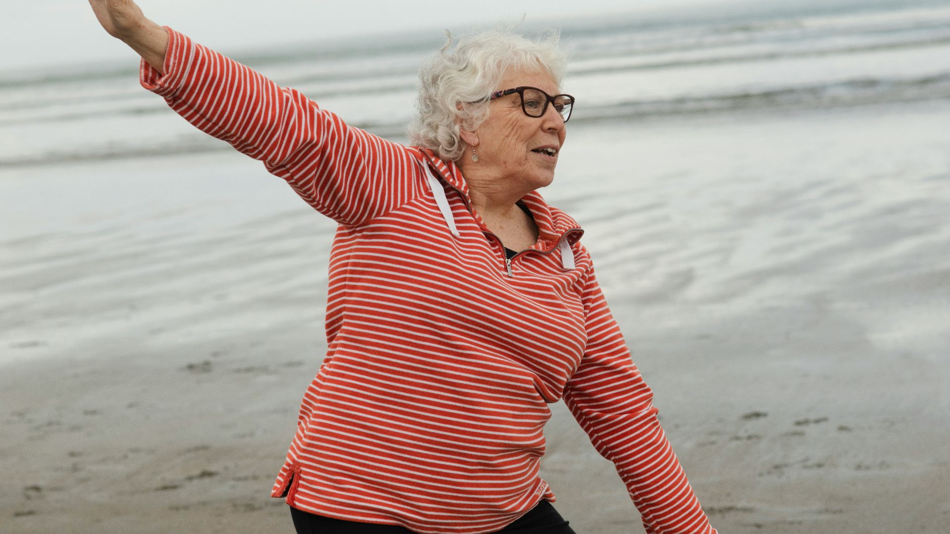 Woman practices tai chi on the beach.
