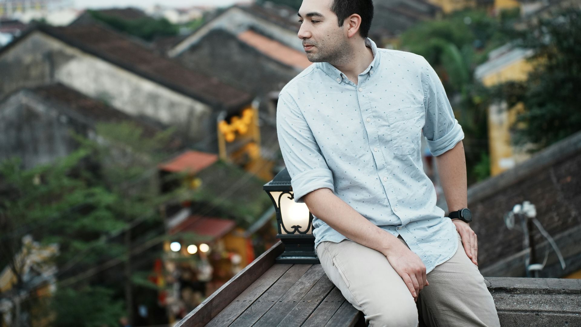 Man sitting on a rooftop overlooking old buildings