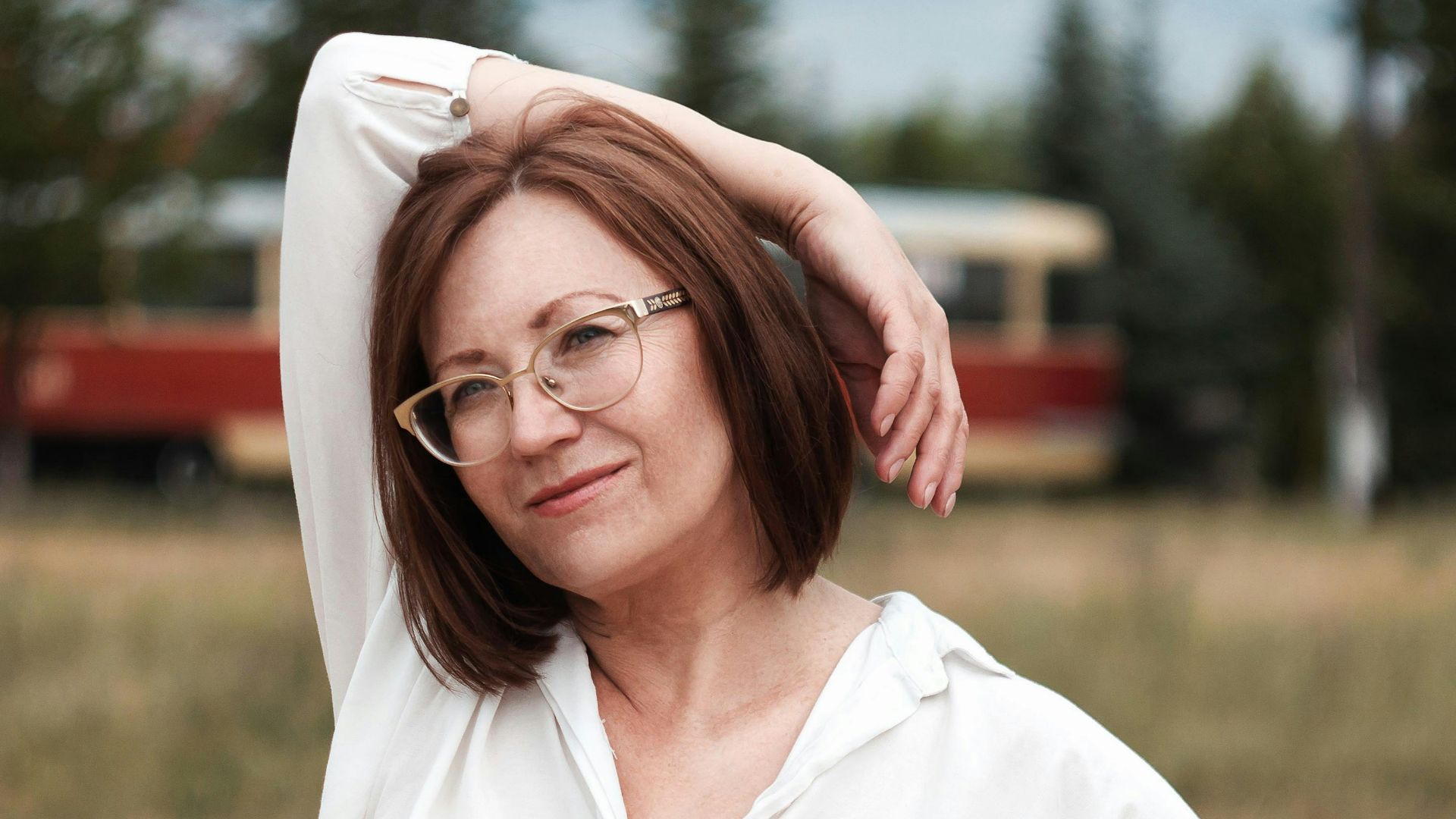 woman in white button up shirt and blue skirt standing on brown sand during daytime