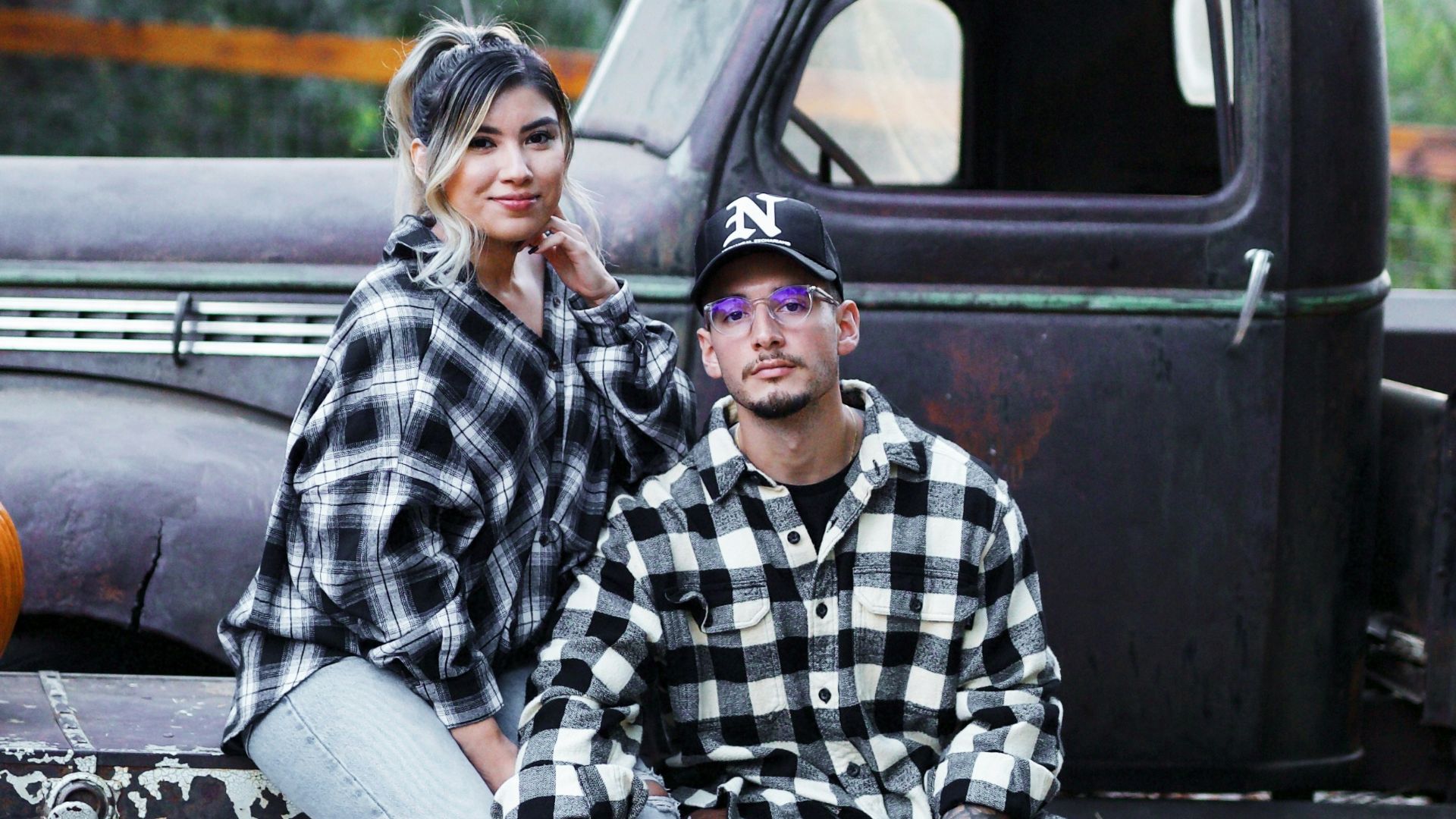 man in black and white checkered dress shirt sitting on black truck during daytime