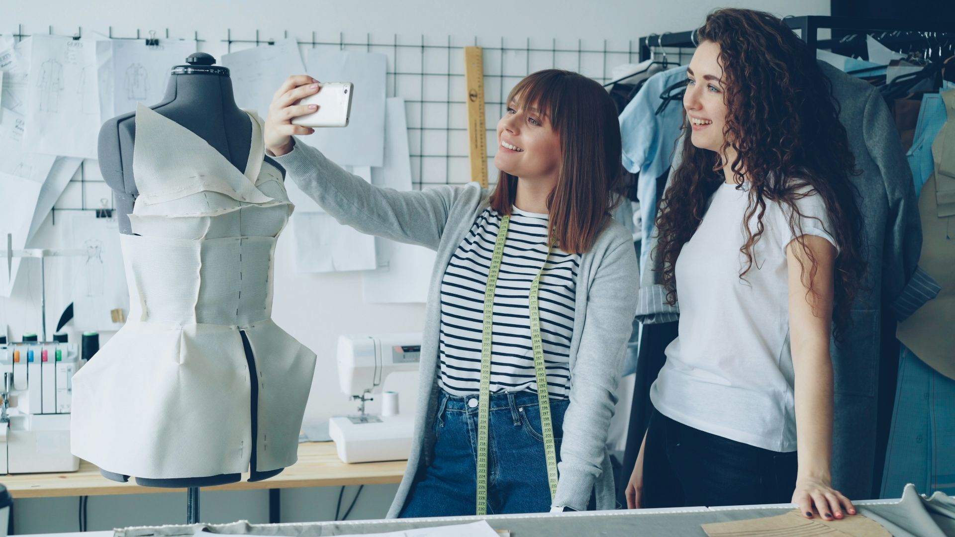 Two fashion designers take a selfie in their studio.