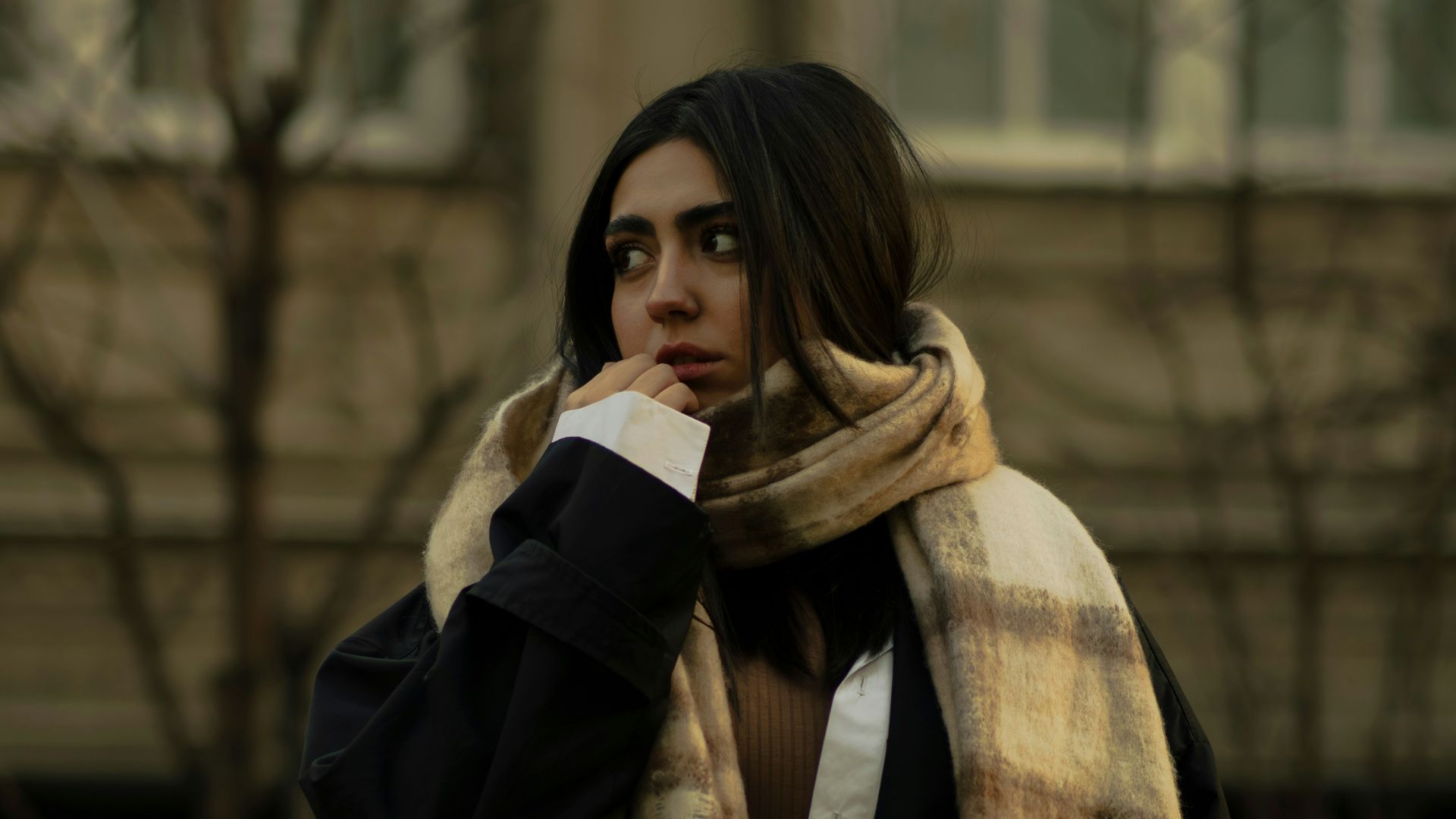 A woman wearing a black coat and a plaid scarf