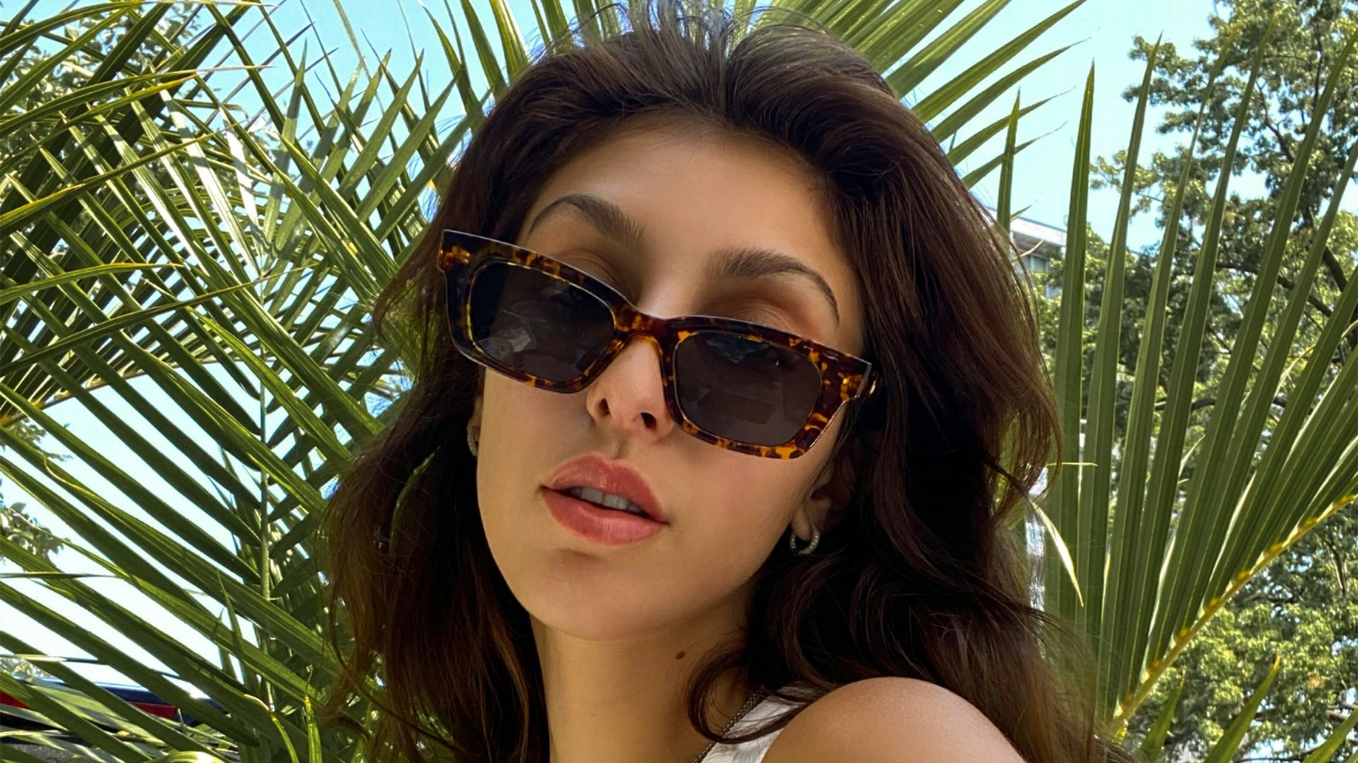 a woman in a white tank top and sunglasses