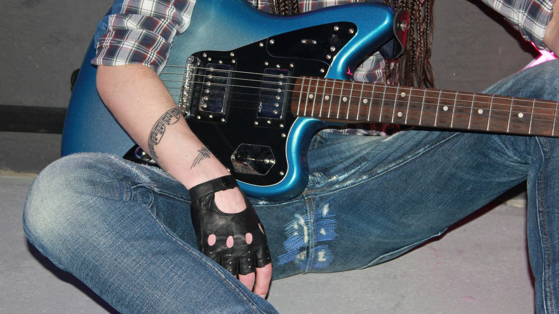 Person in jeans holding a blue electric guitar