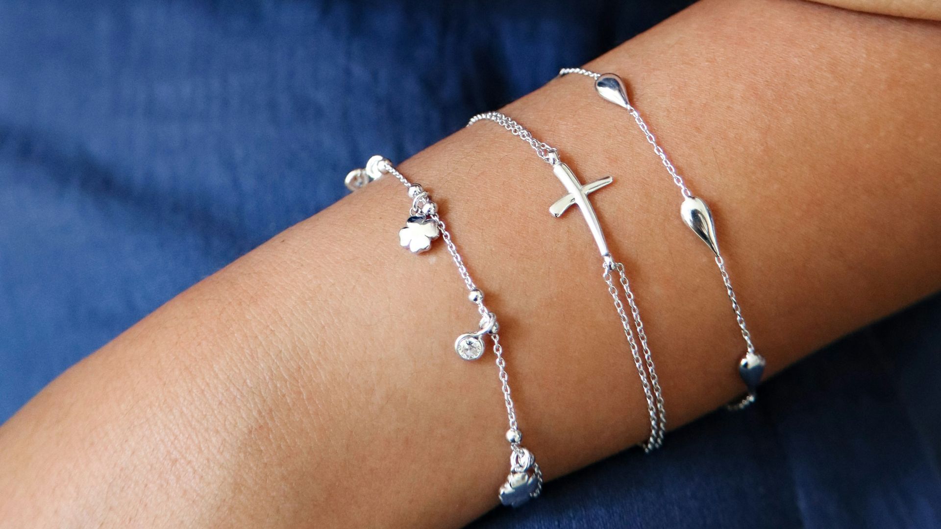 Two arms adorned with delicate silver bracelets.