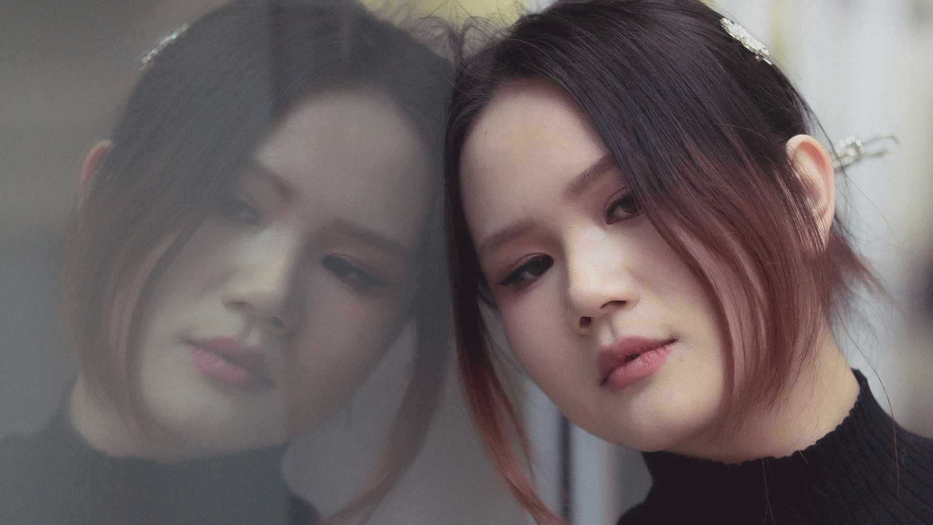 a woman standing in front of a window next to another woman