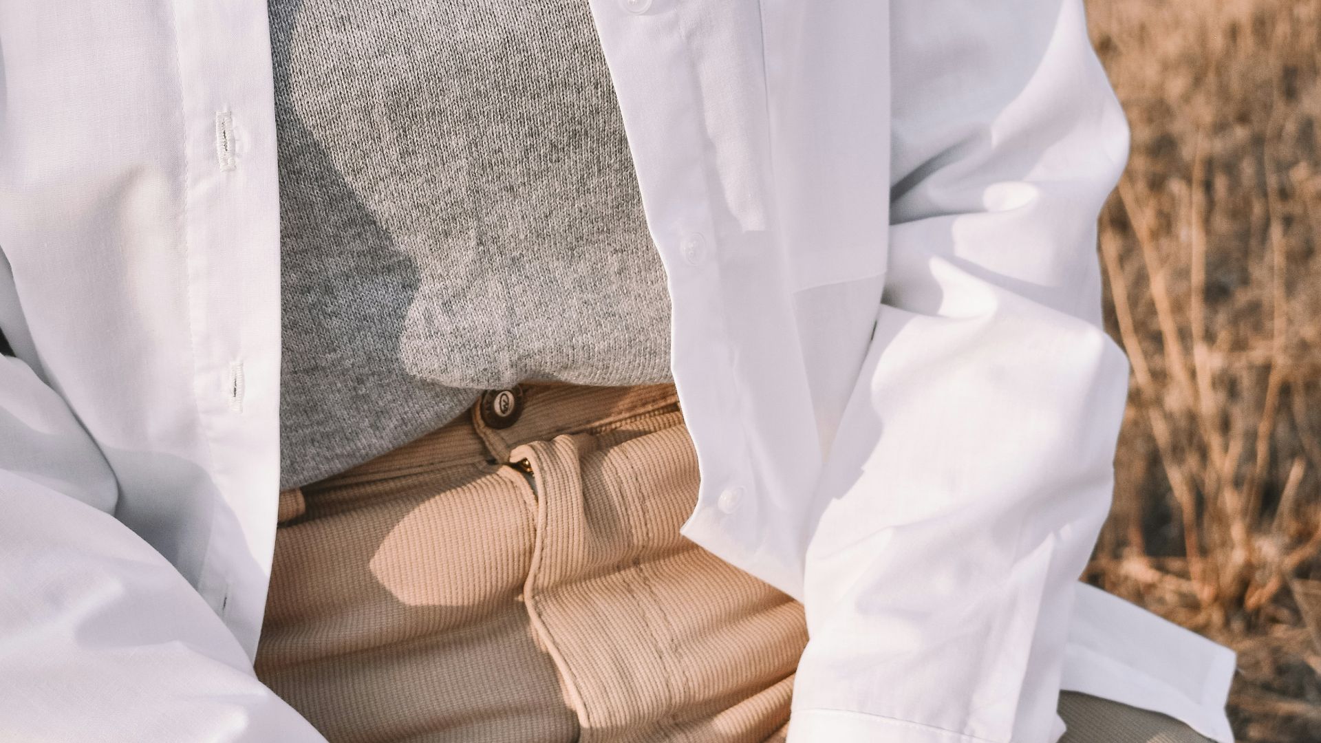 man in white button up long sleeve shirt and brown pants sitting on brown wooden bench