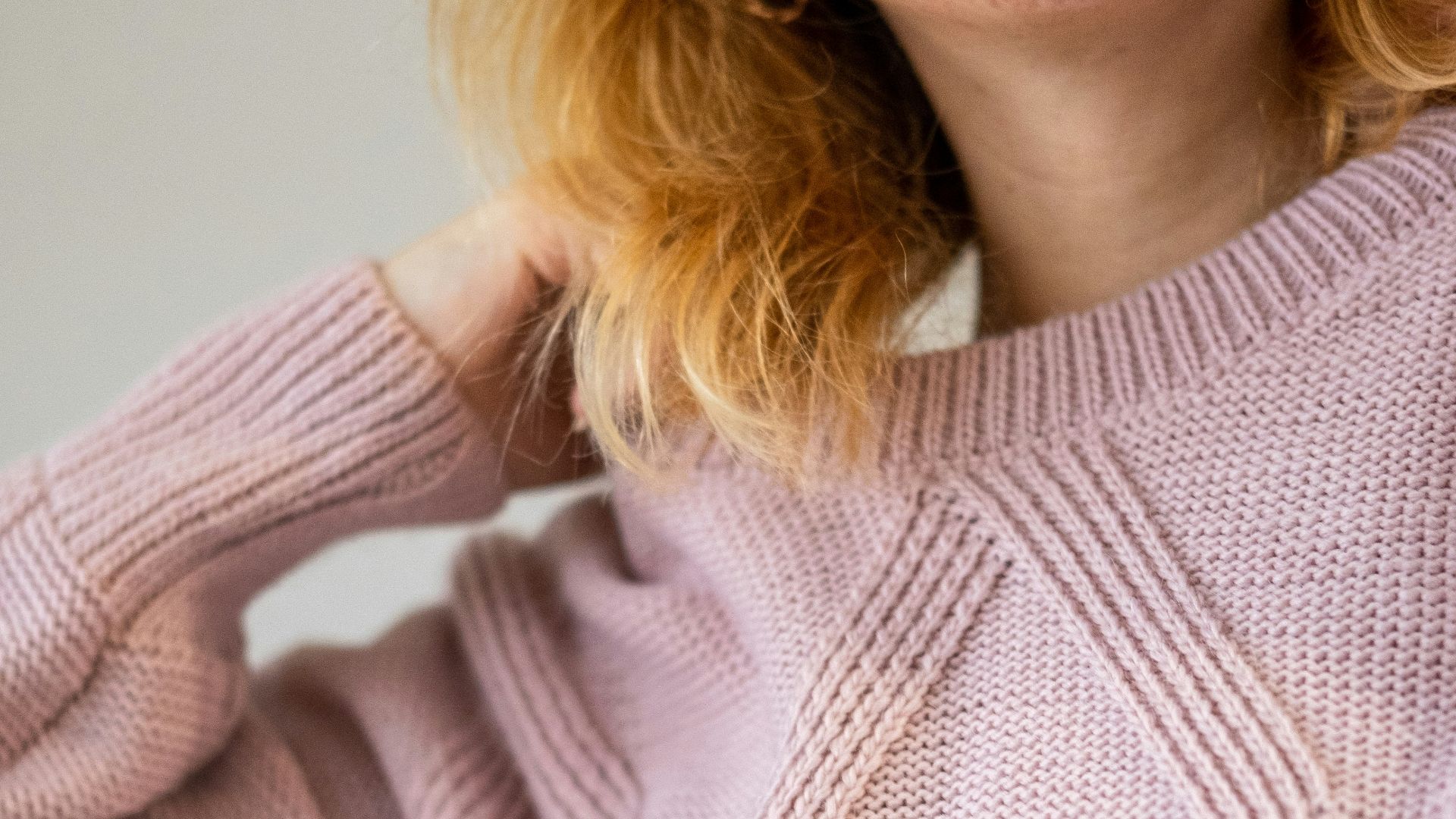 a woman with red hair wearing a pink sweater