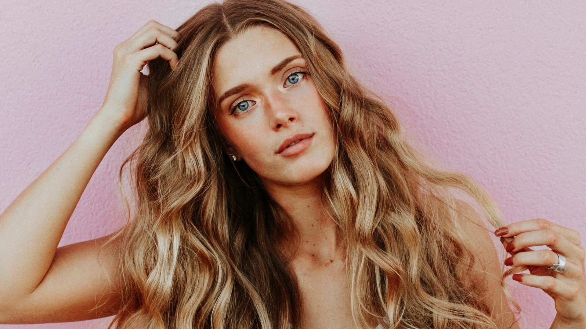 woman standing next to pink wall while scratching her head