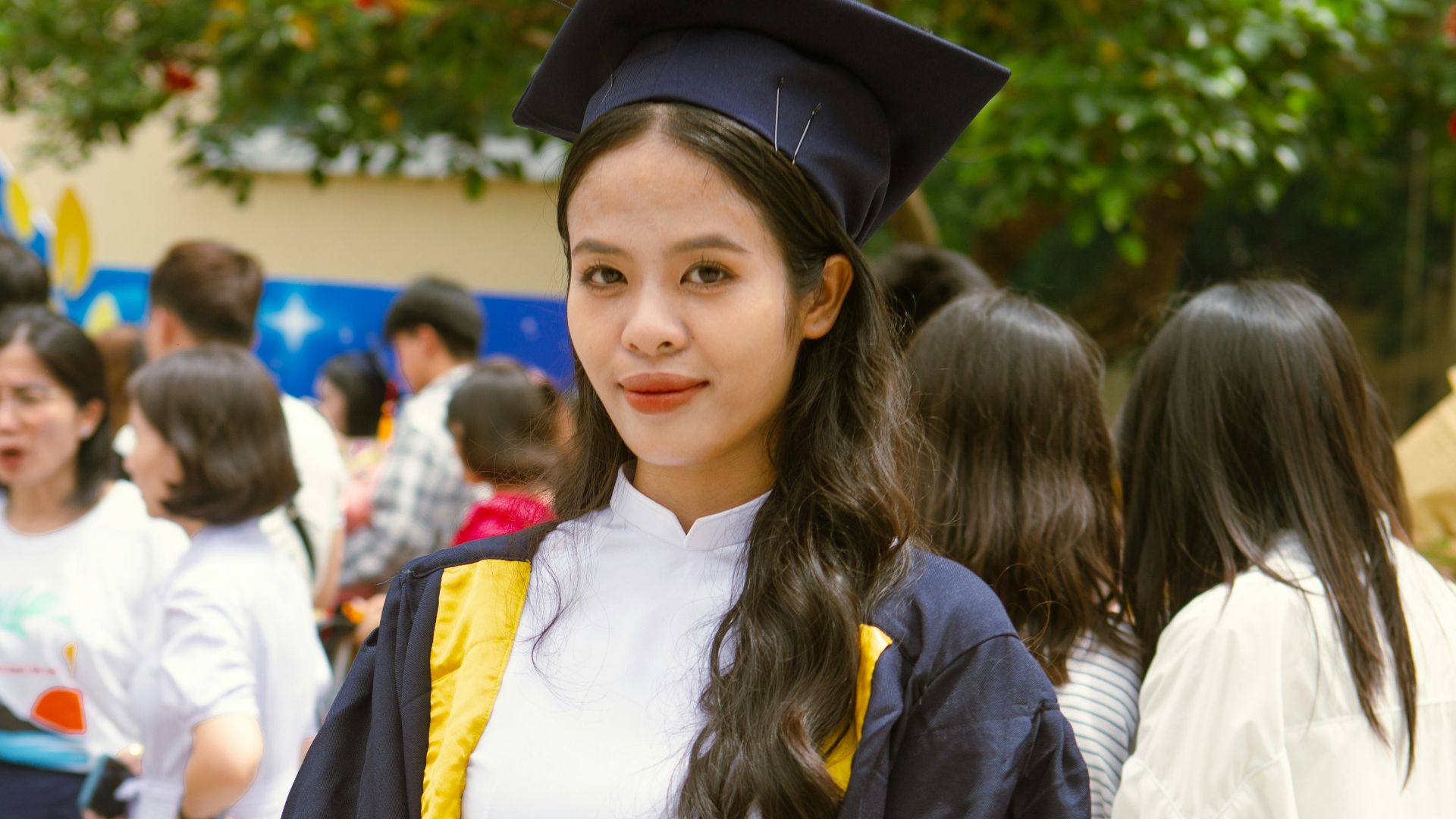 a woman in a graduation gown holding a teddy bear