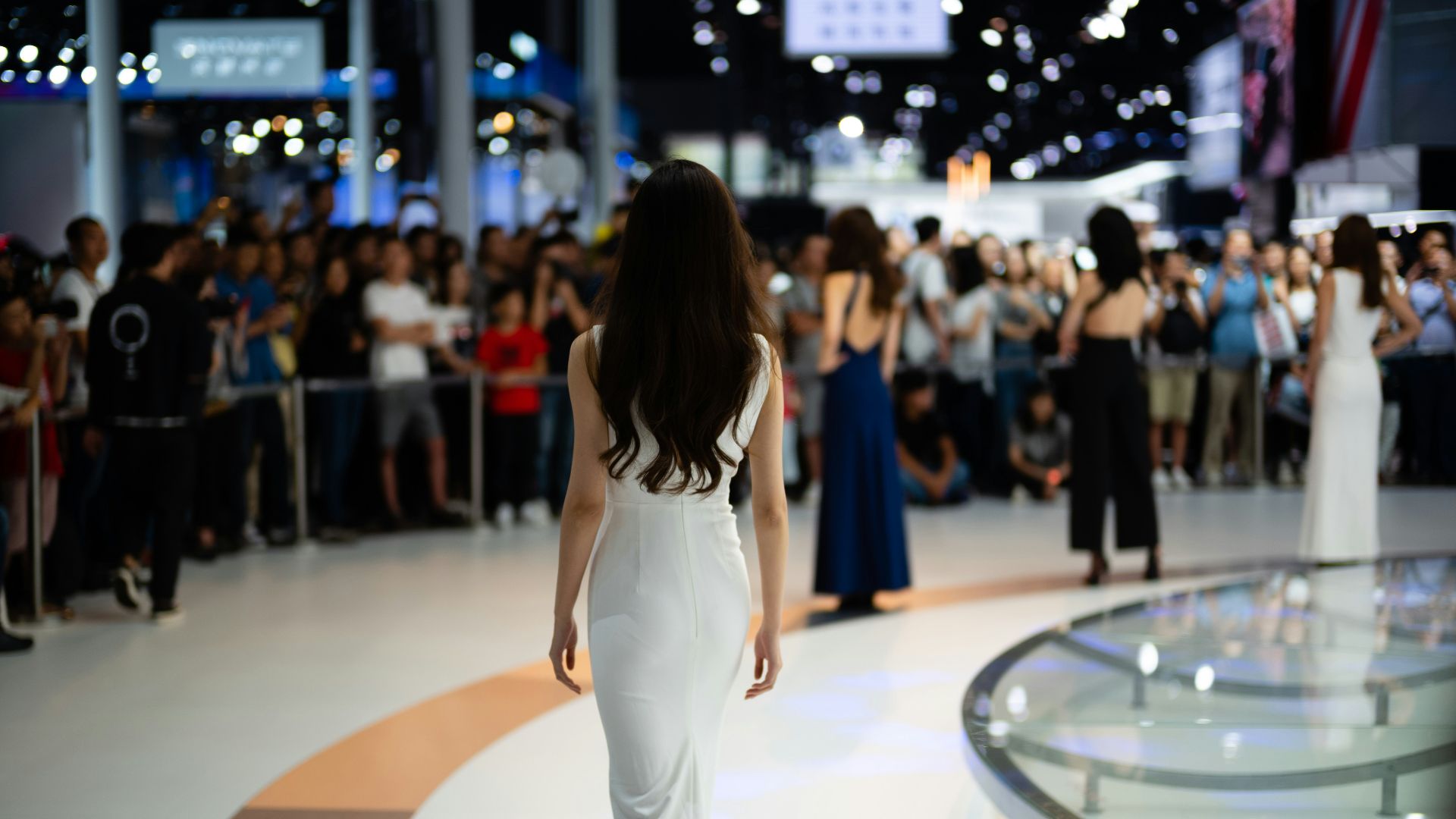 Woman in white dress walks on stage
