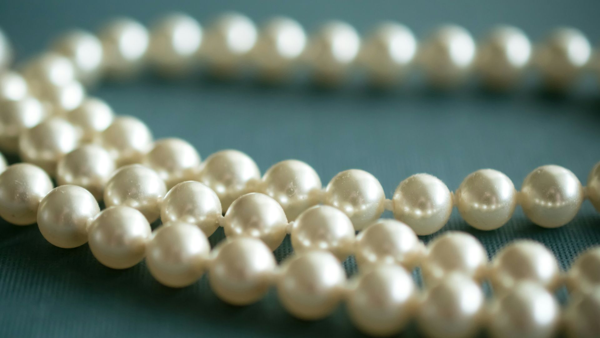 white pearl necklace on gray textile