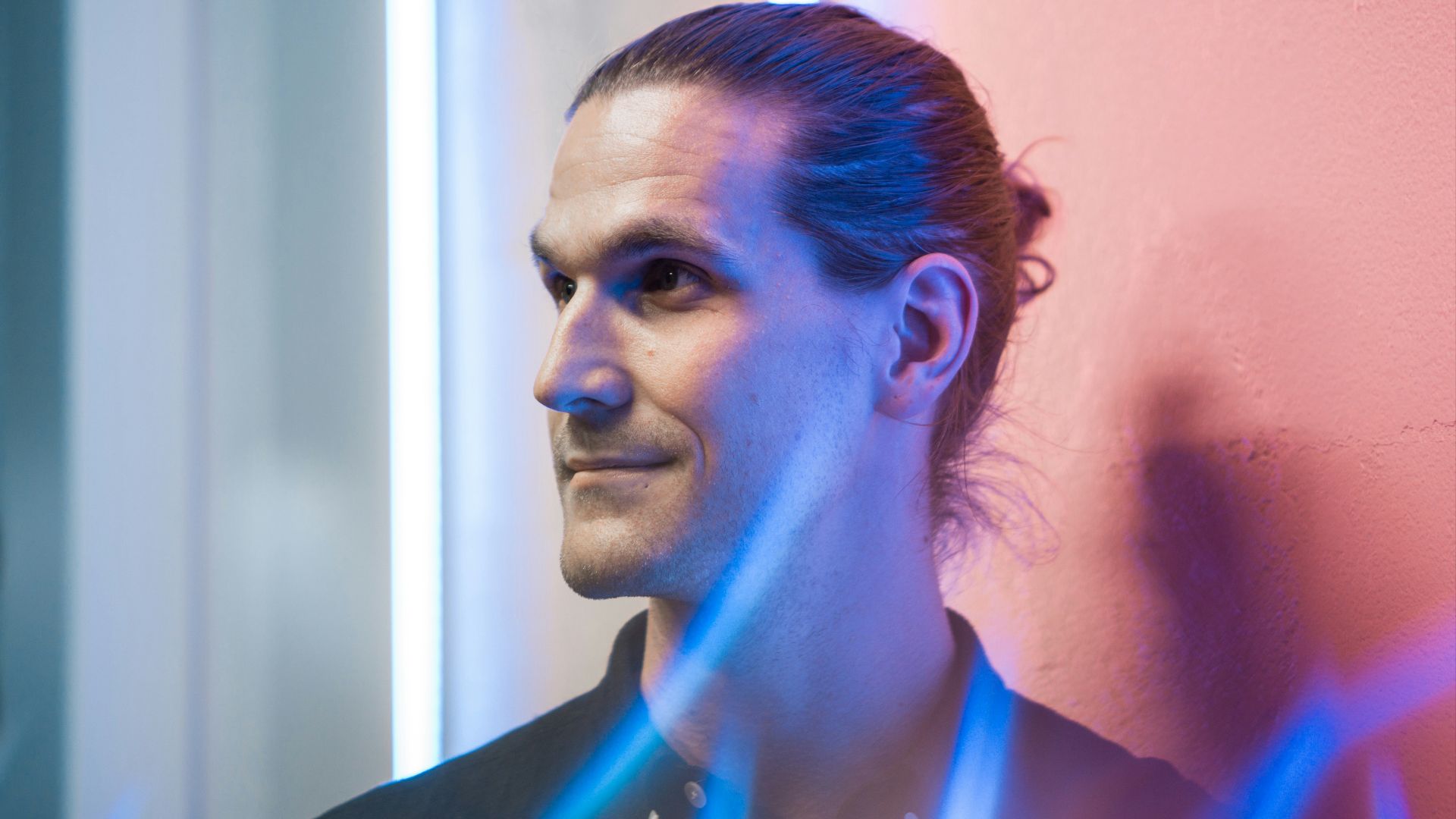 man in black collared shirt leaning near wall