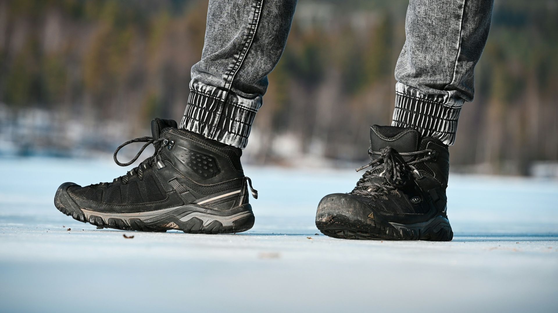 a person standing on a snowy surface wearing black shoes