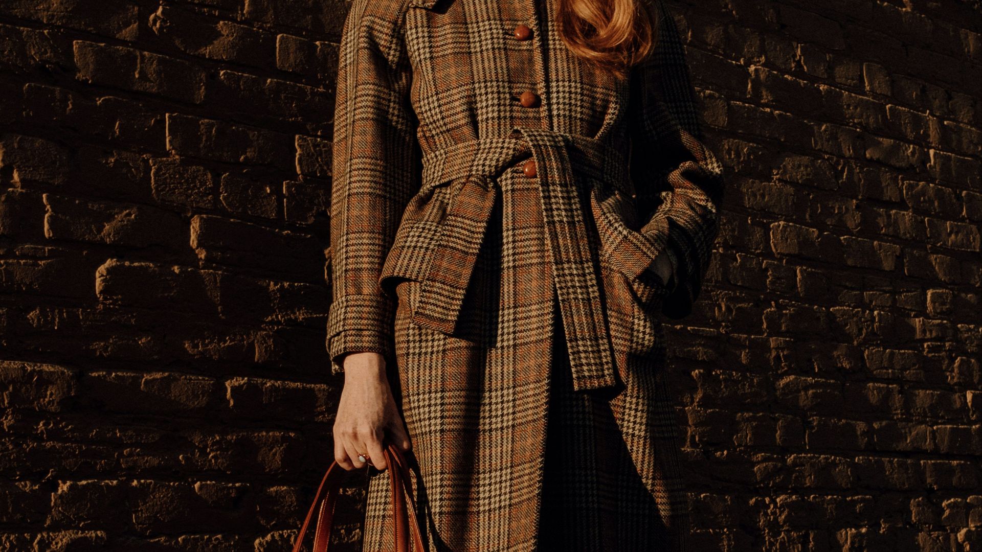 woman in brown coat holding brown leather handbag
