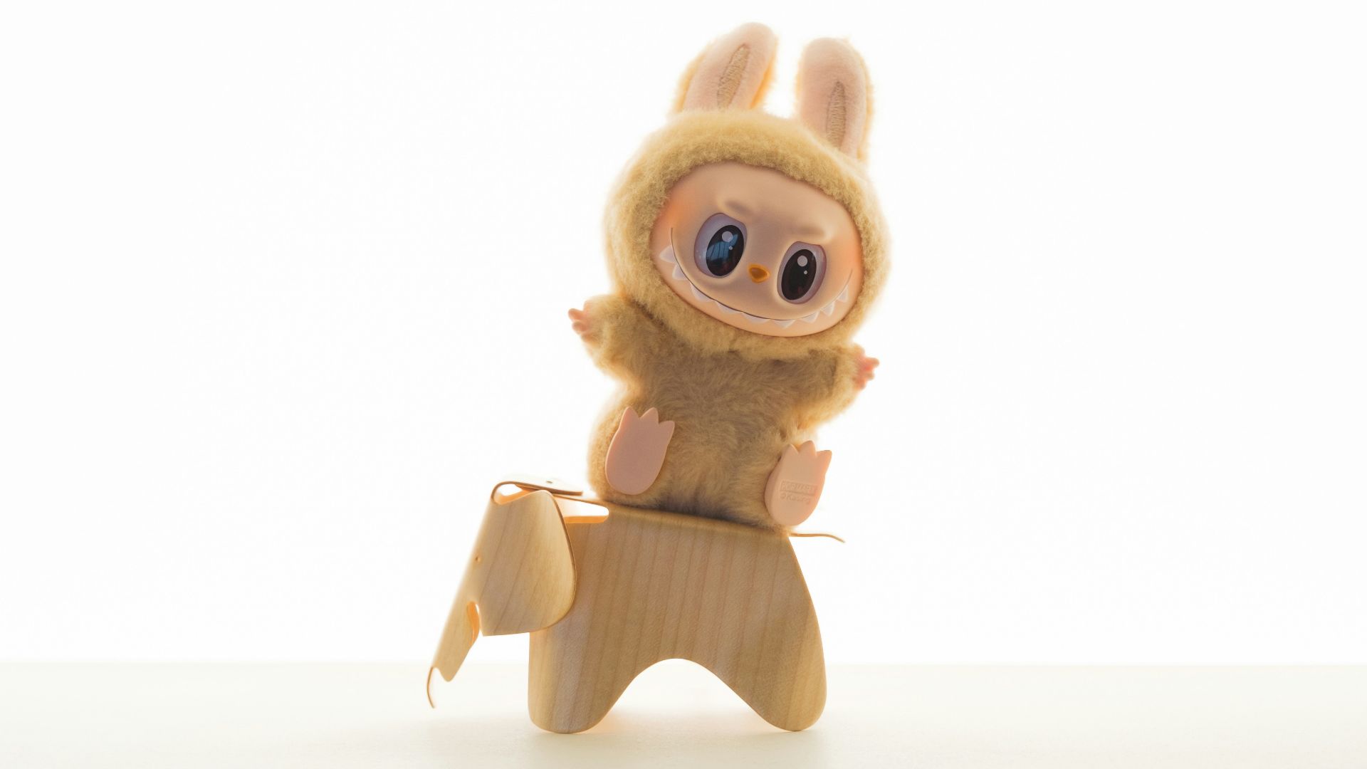A plush toy rides a wooden animal.