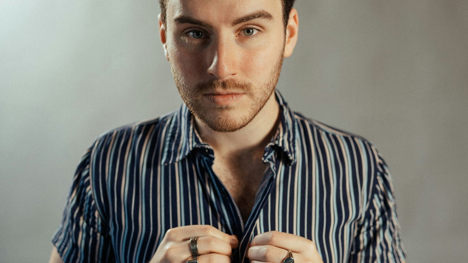 a man in a striped shirt tying his tie