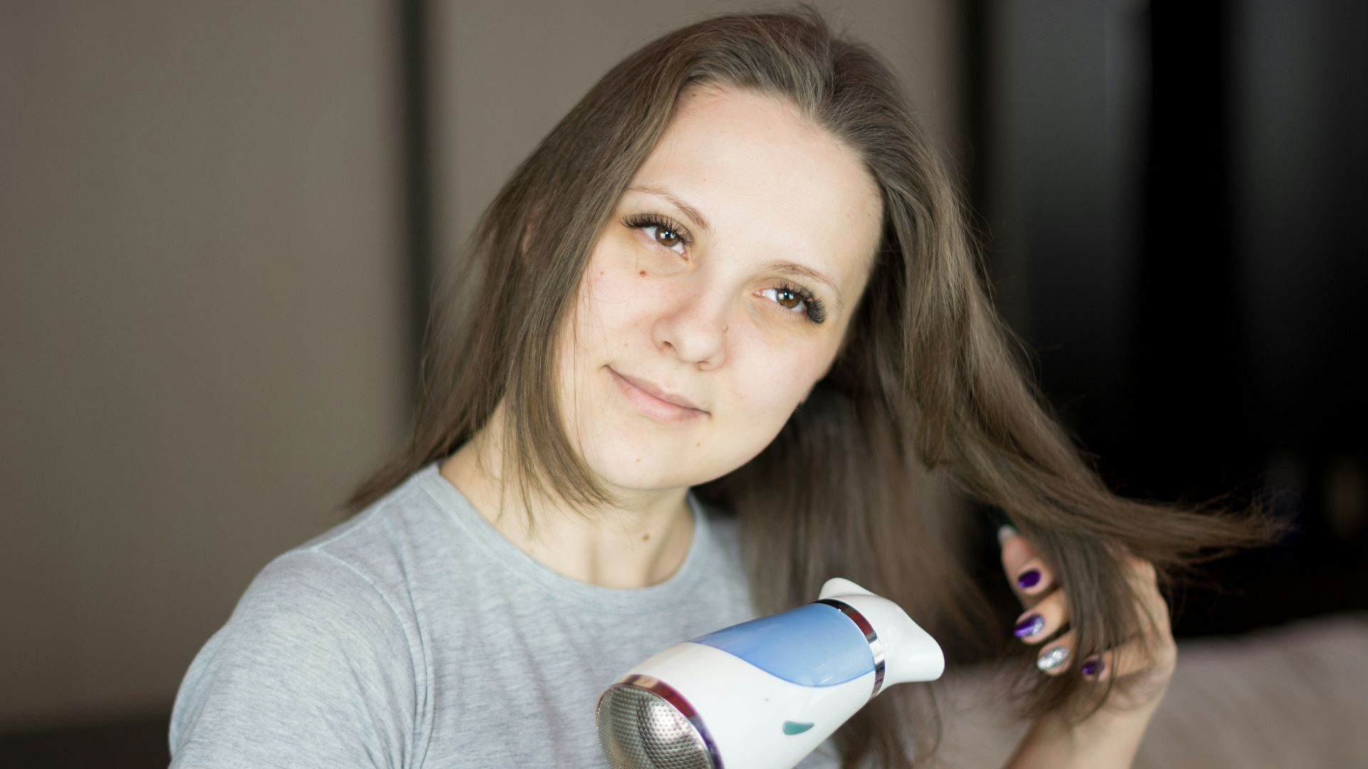 a woman blow drying her hair with a hair dryer