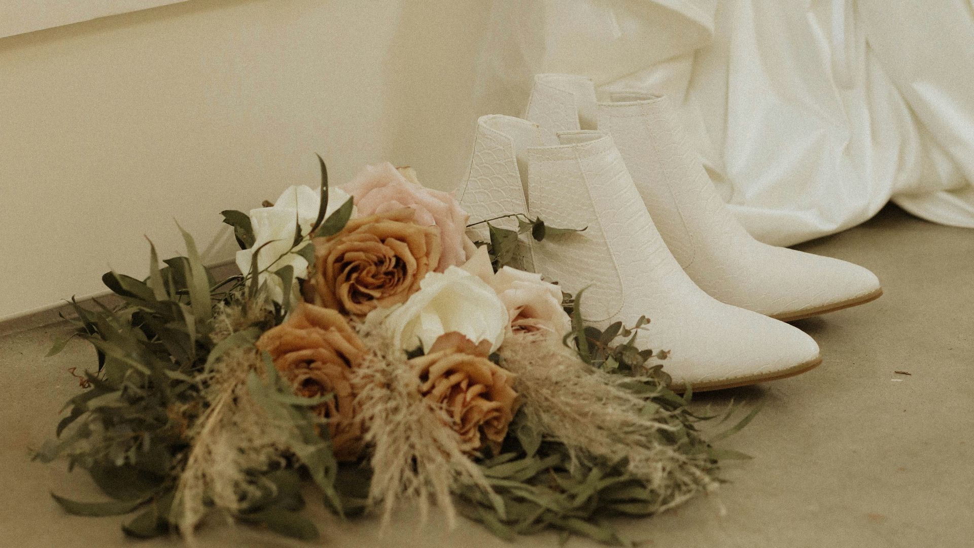 a pair of white shoes next to a bouquet of flowers
