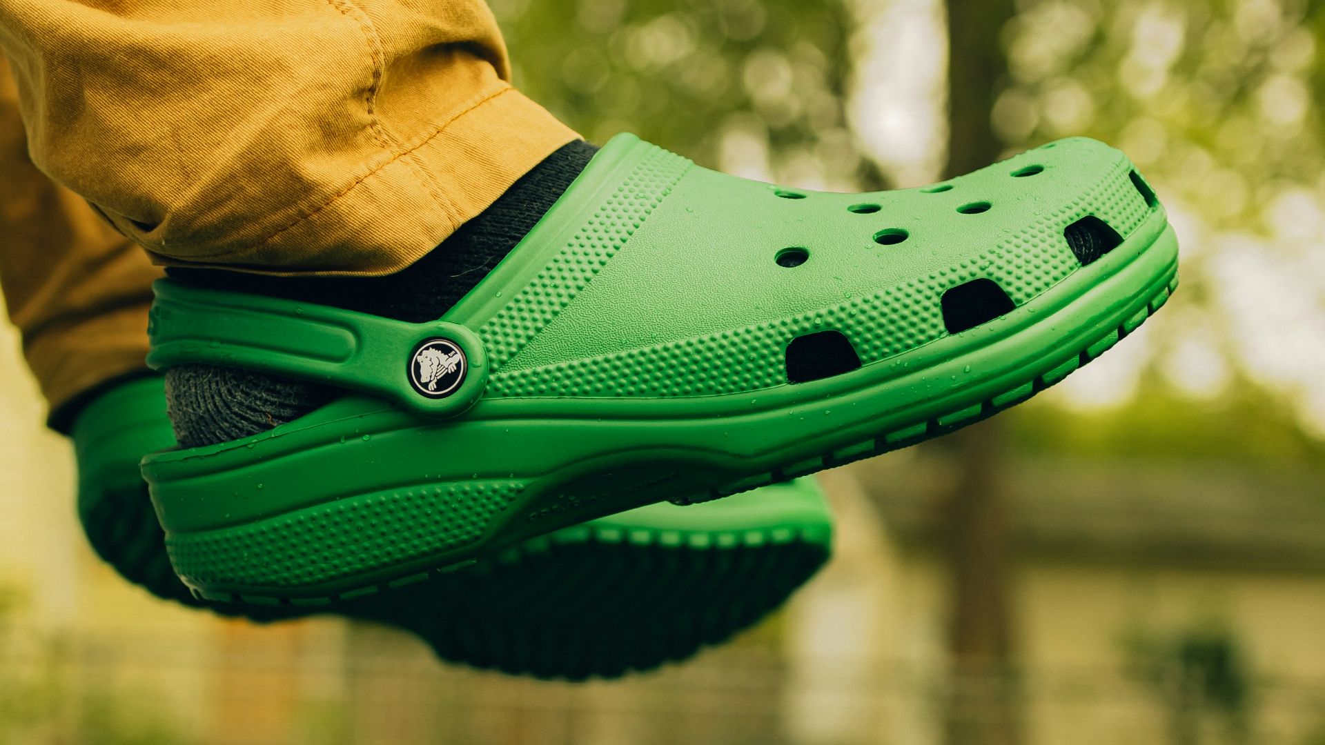 a person wearing a green clogger shoe in a park