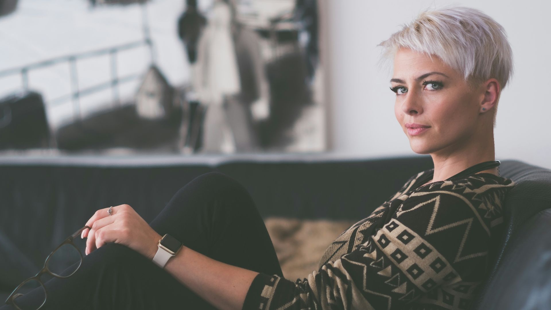 woman sitting on sofa holding eyeglasses