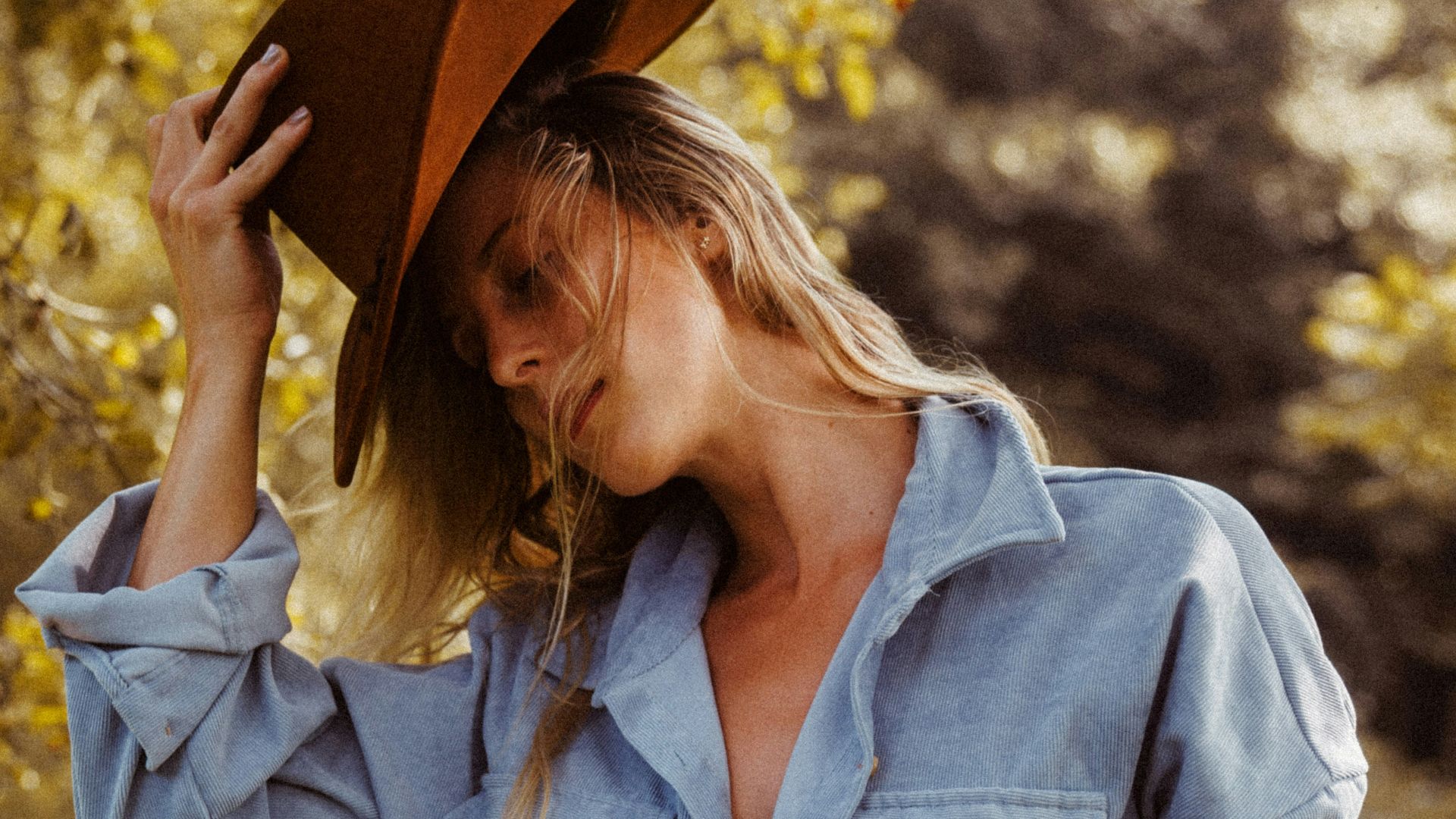 a woman in a blue shirt dress and a cowboy hat