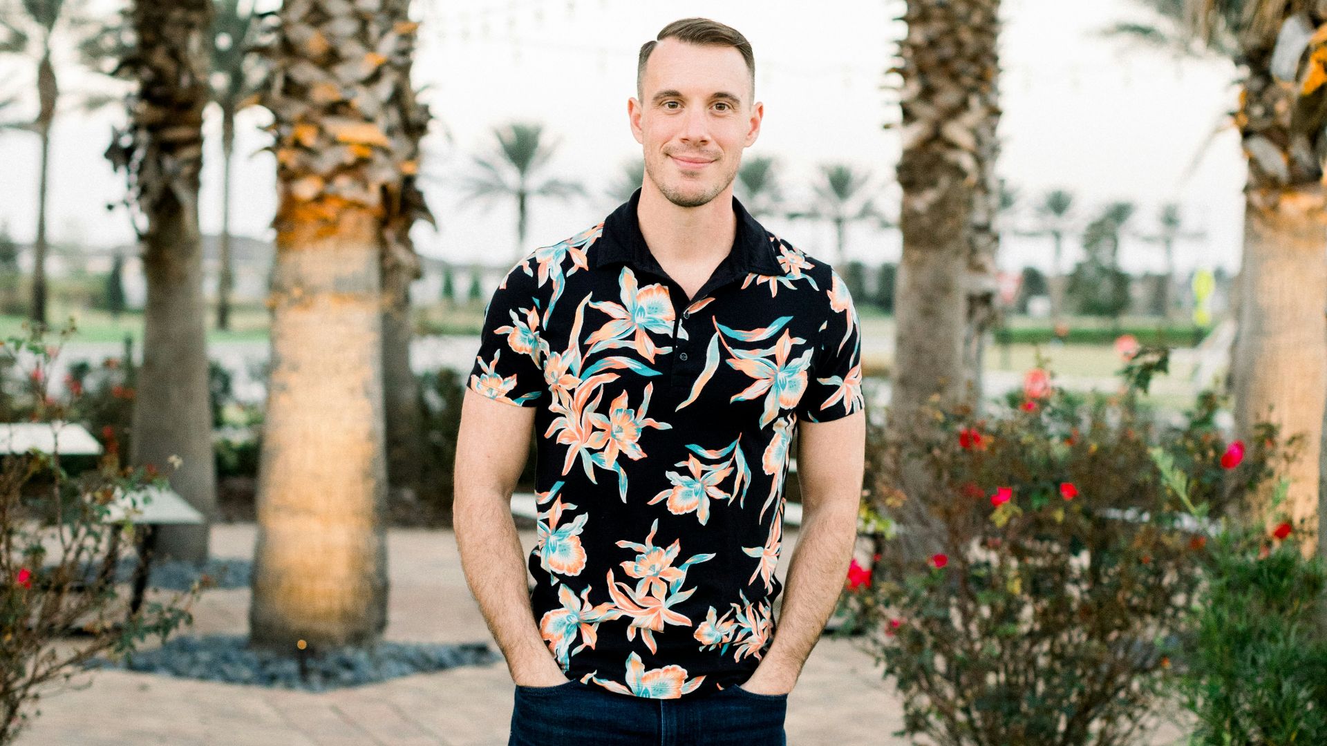 a man standing on a sidewalk in front of palm trees